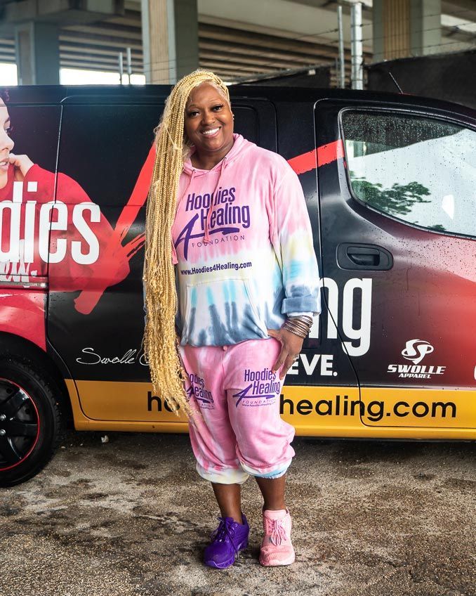 A woman with long blonde hair is standing in front of a van.