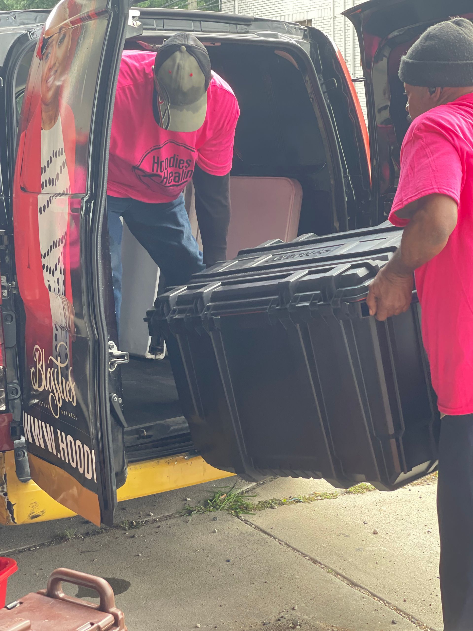 A man in a pink shirt is carrying a large black box