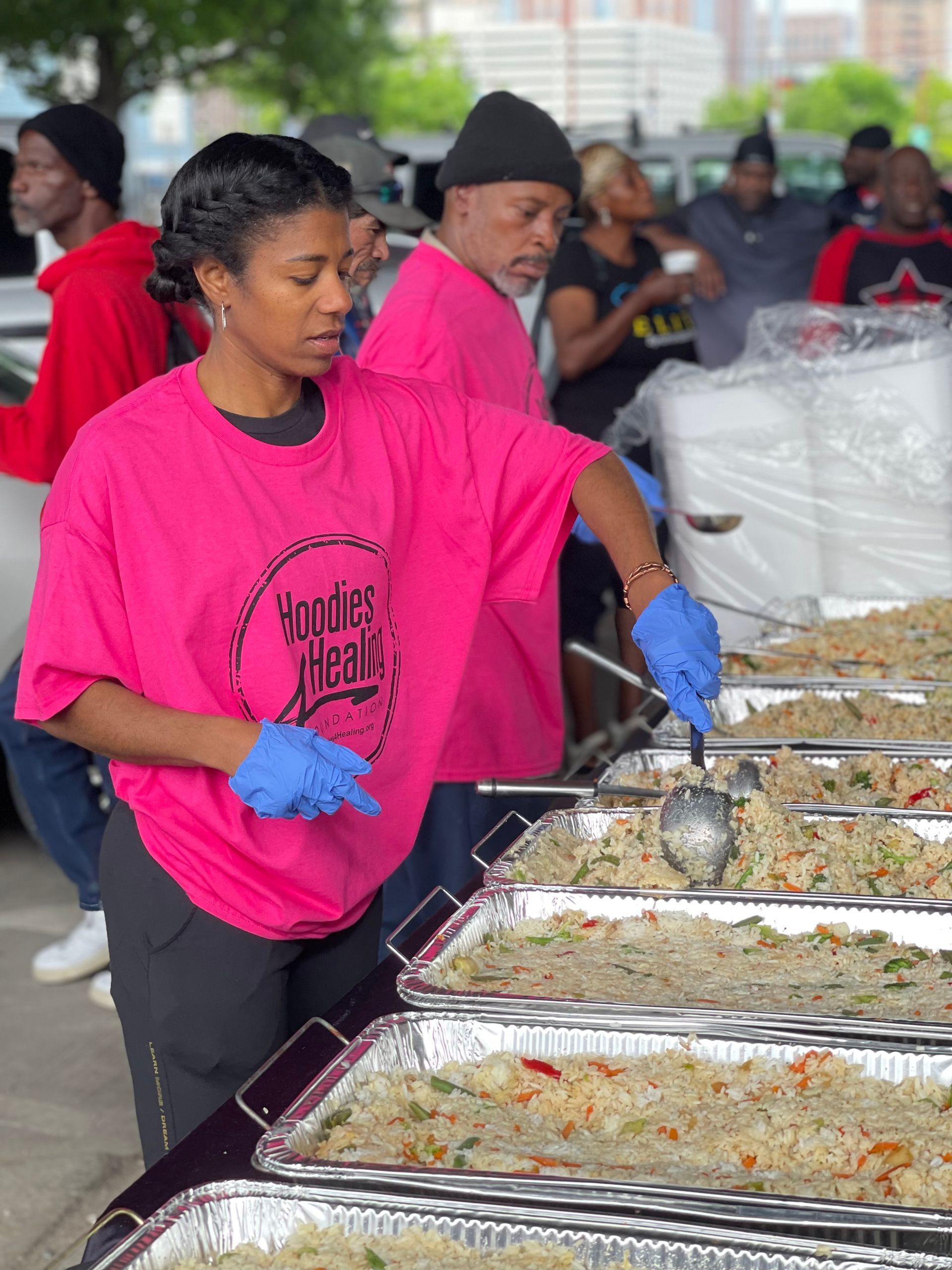 A woman in a pink shirt is serving food at a buffet