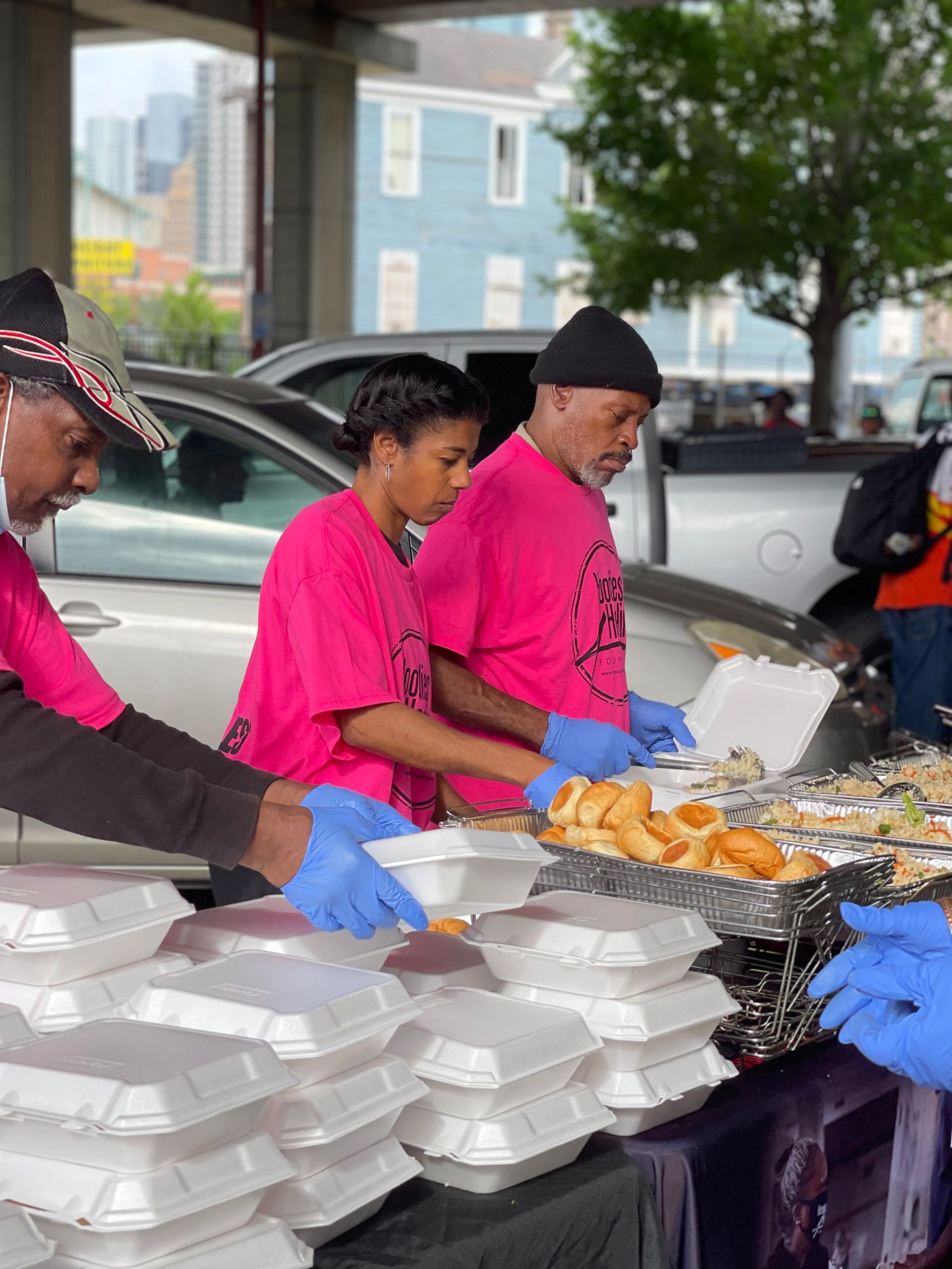 A group of people are standing around a table with containers of food.