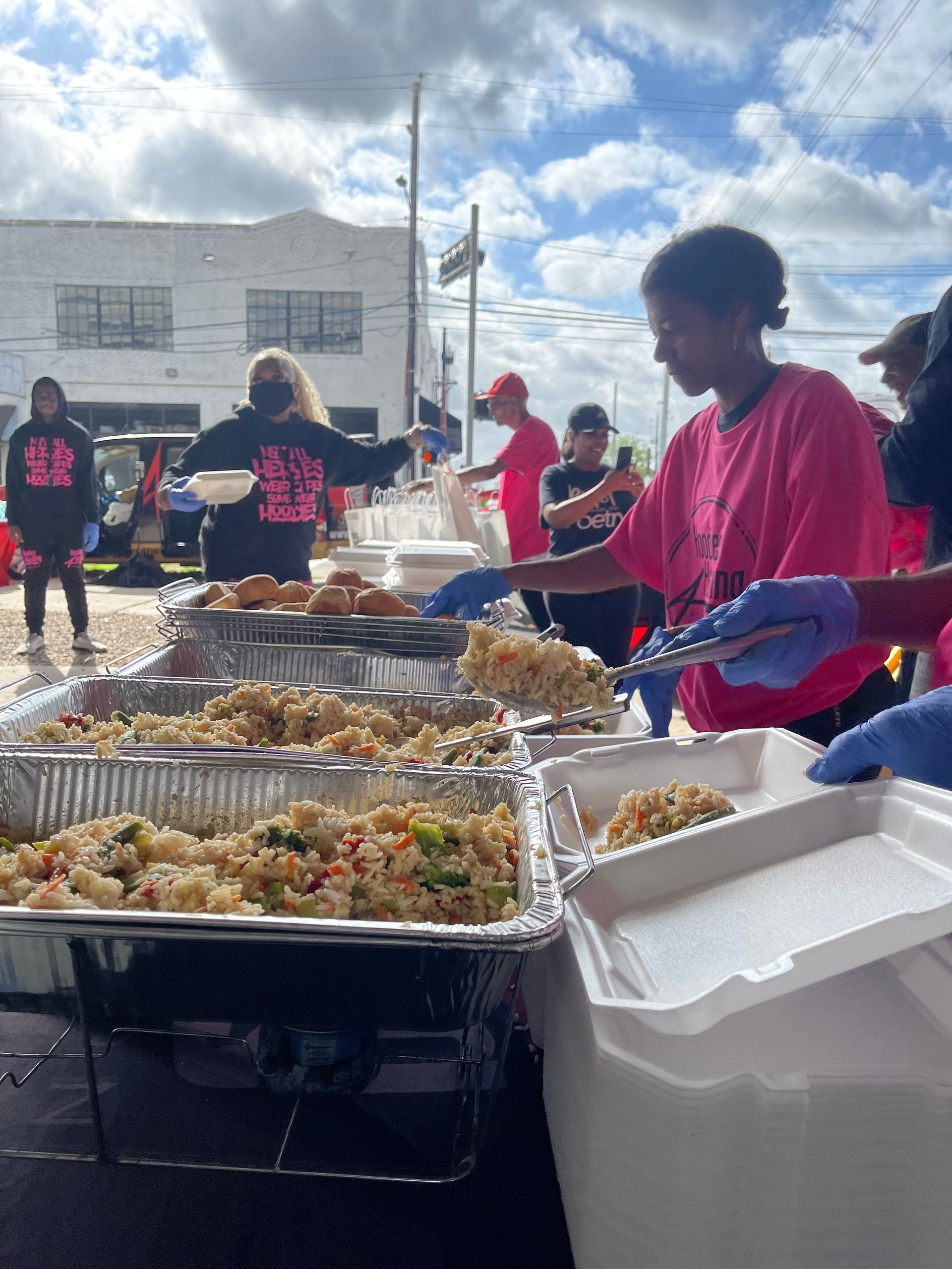 A group of people are standing around a table serving food.