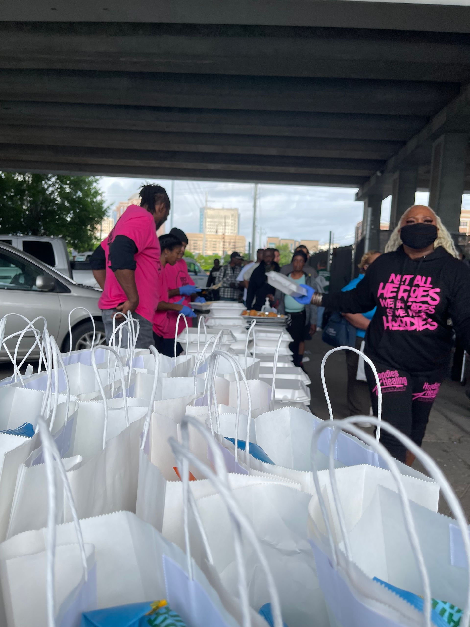A group of people are standing in a parking lot filled with bags.
