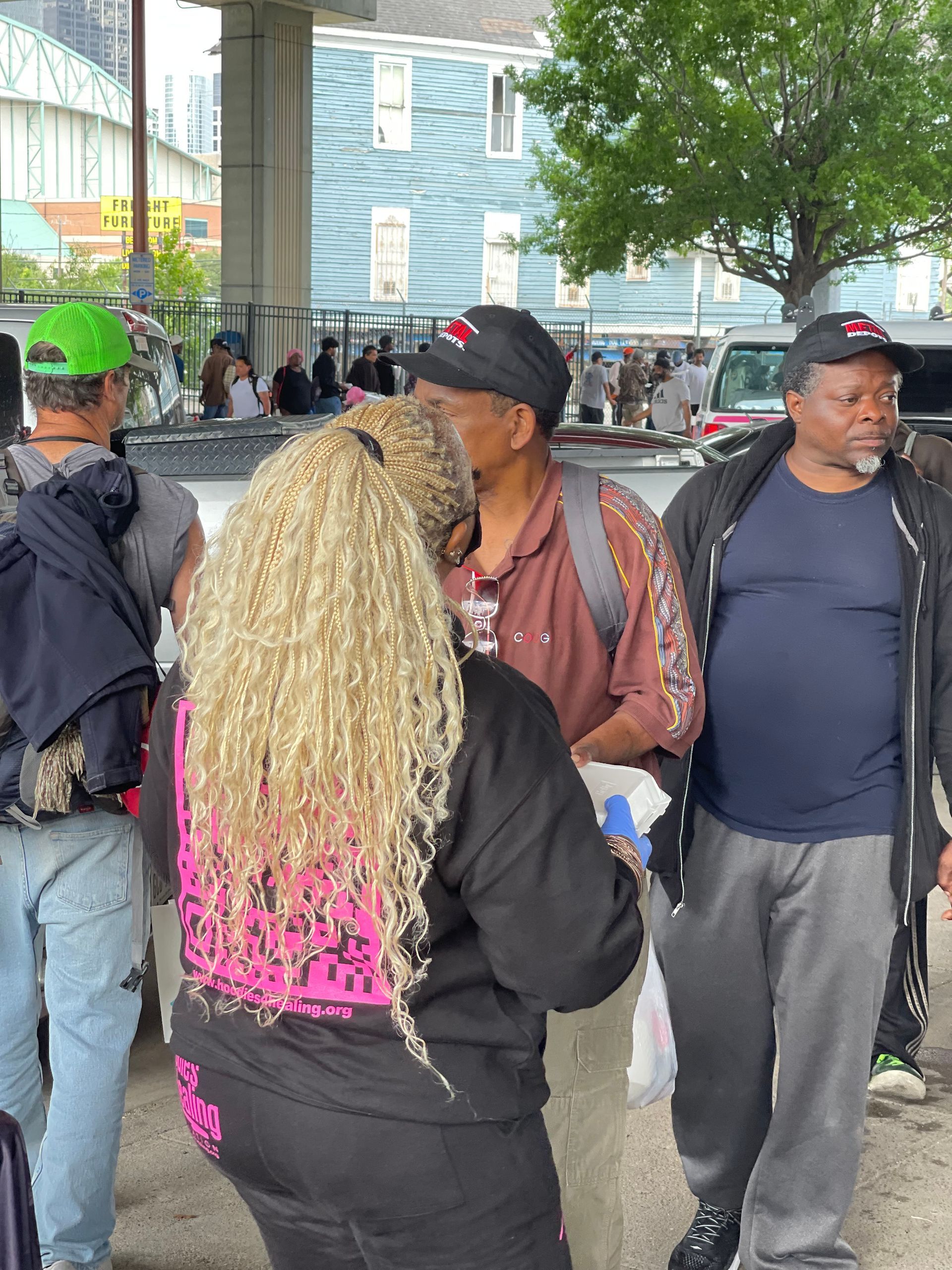 A group of people are standing in a parking lot talking to each other.