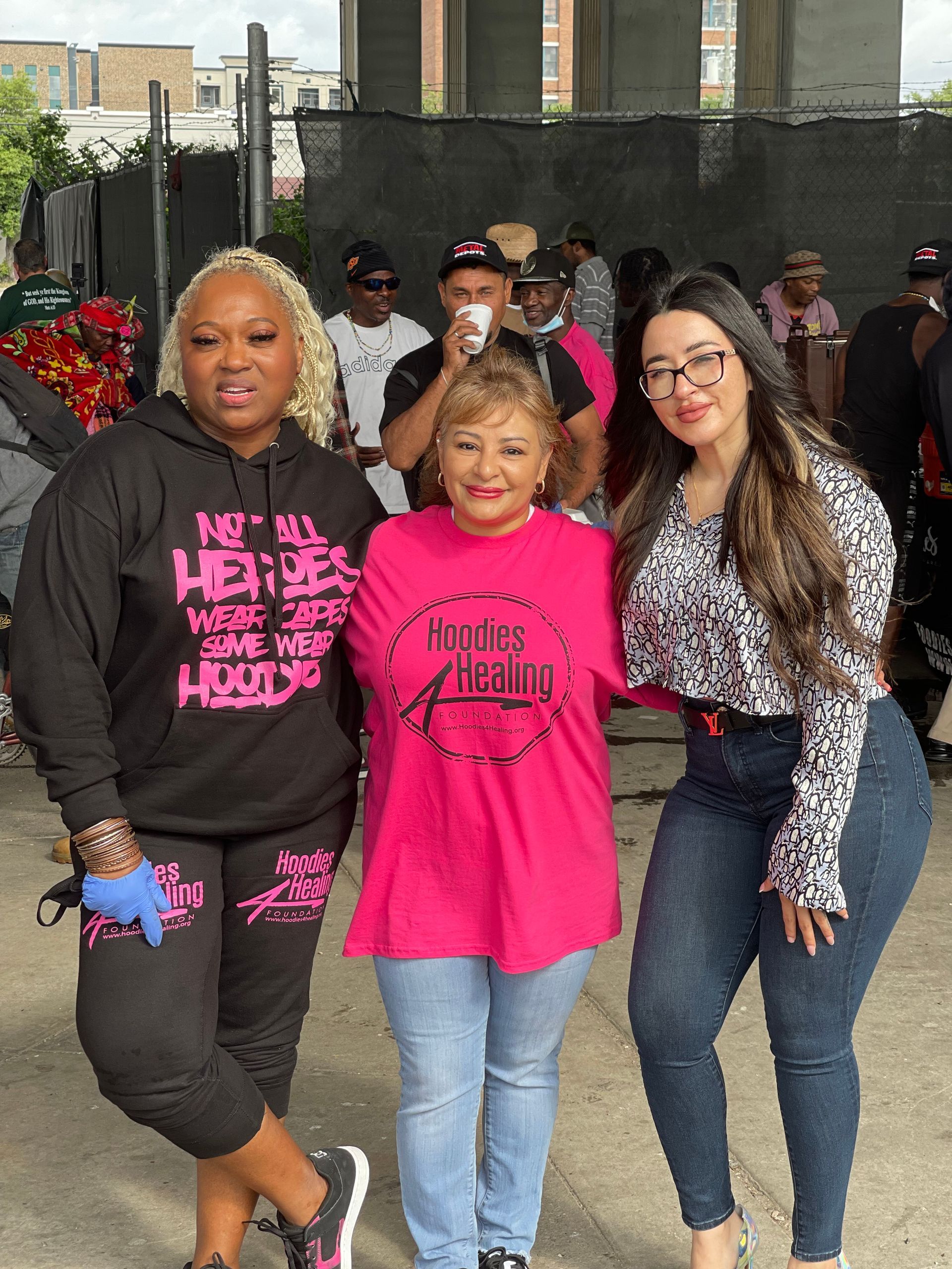 Three women are posing for a picture in front of a crowd.