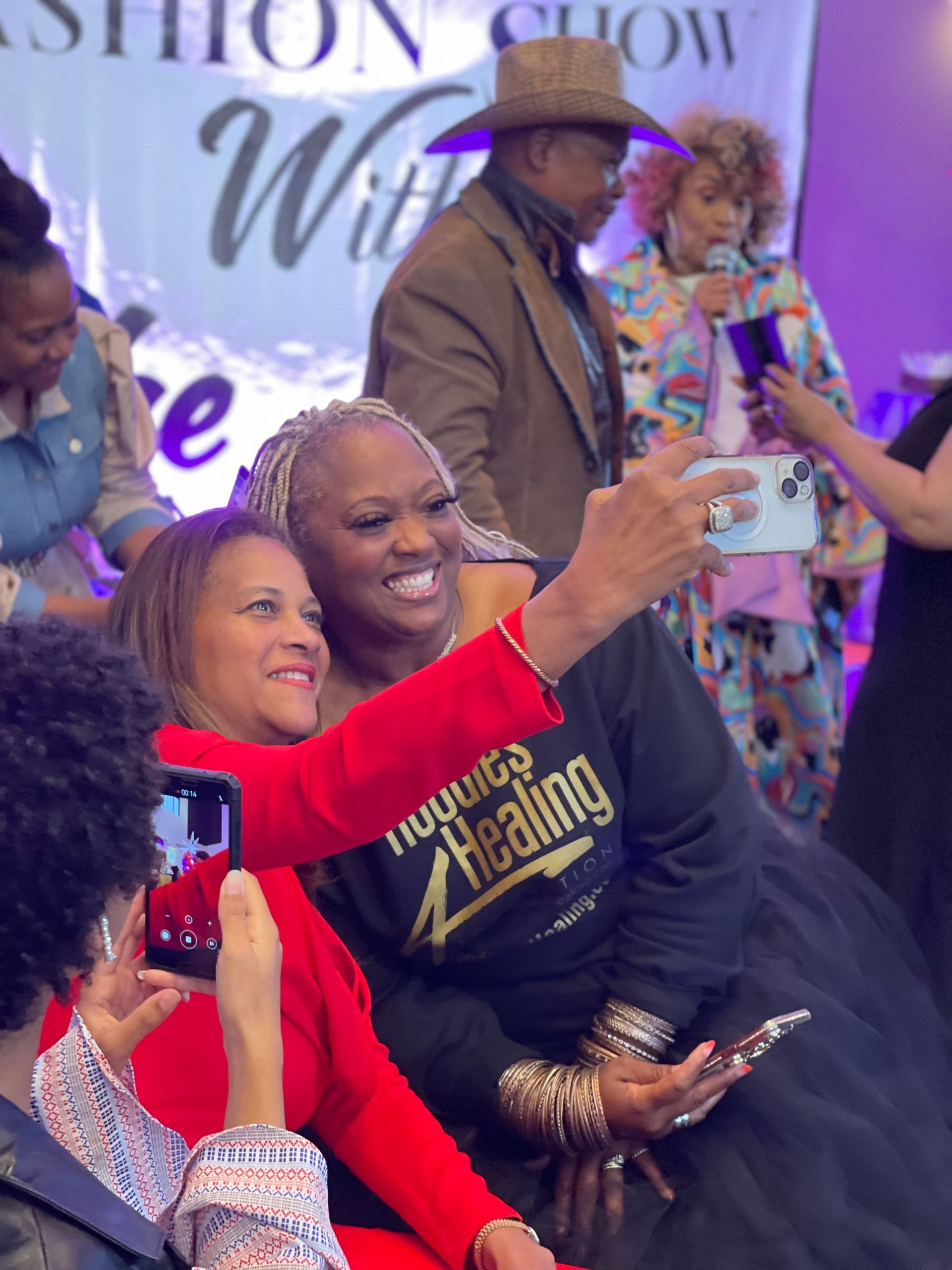 A woman wearing a shirt that says healing is taking a selfie with another woman