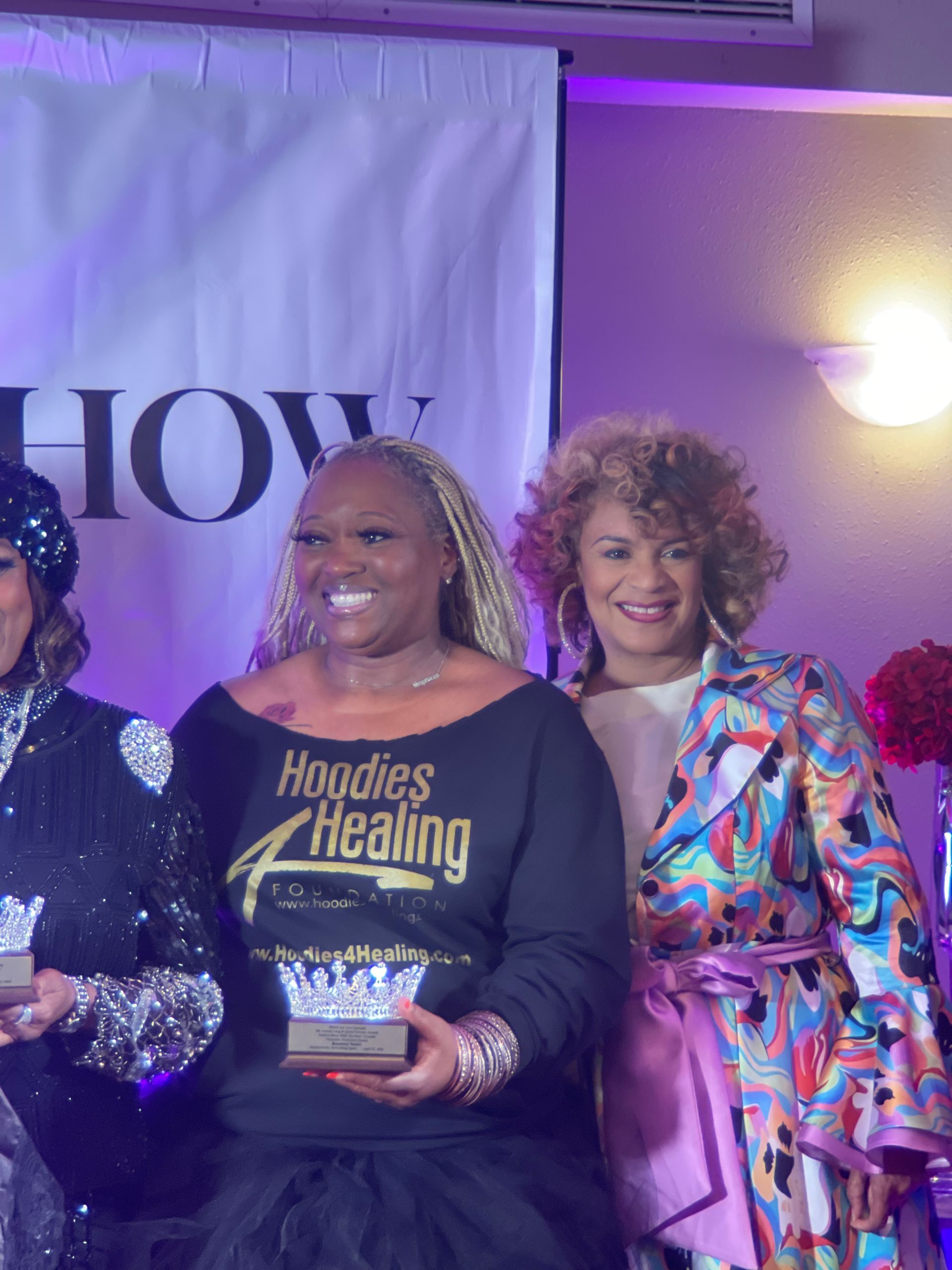 Three women are standing next to each other and one of them is holding a trophy.