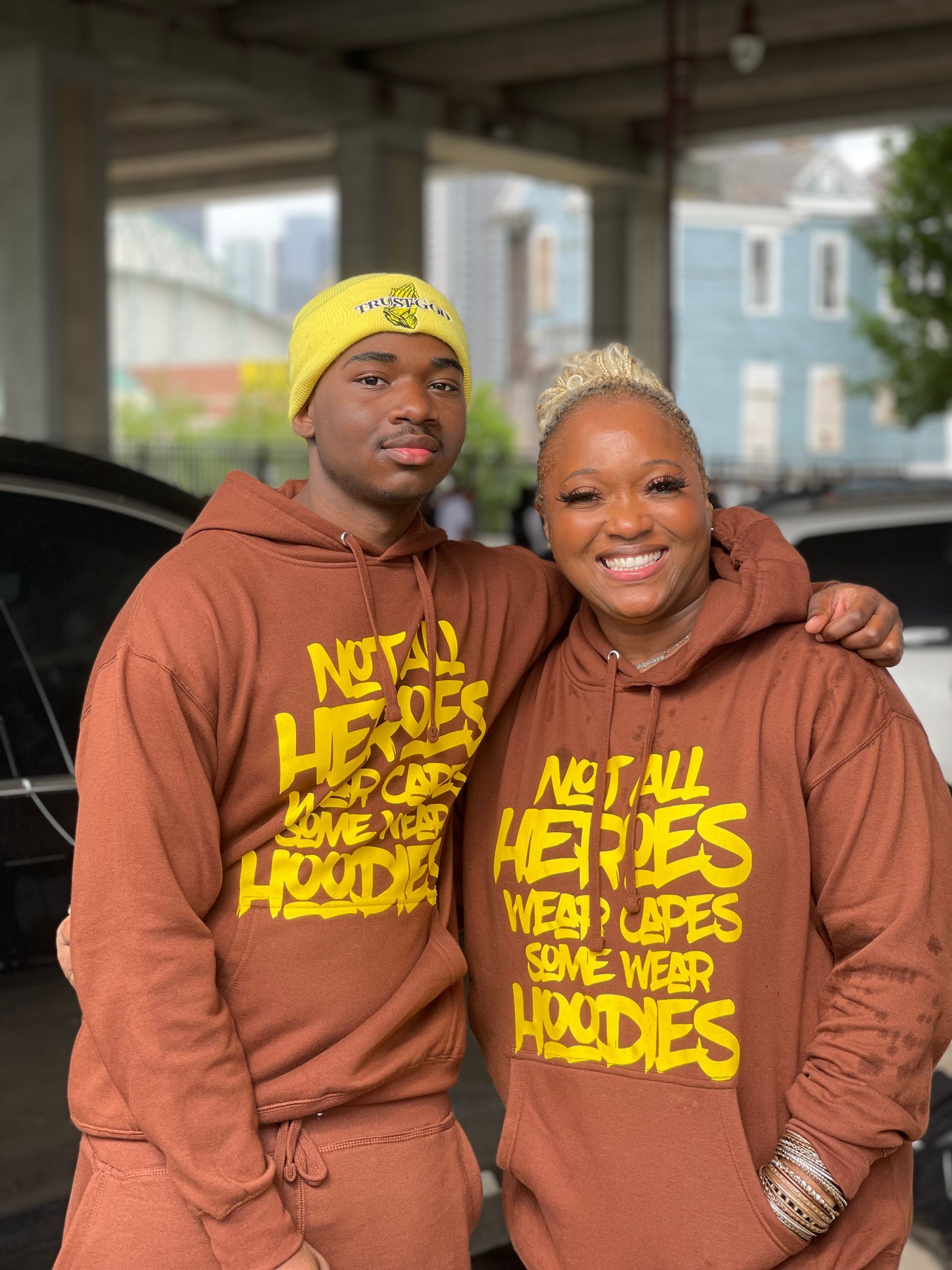 A man and a woman are standing next to each other wearing matching hoodies.