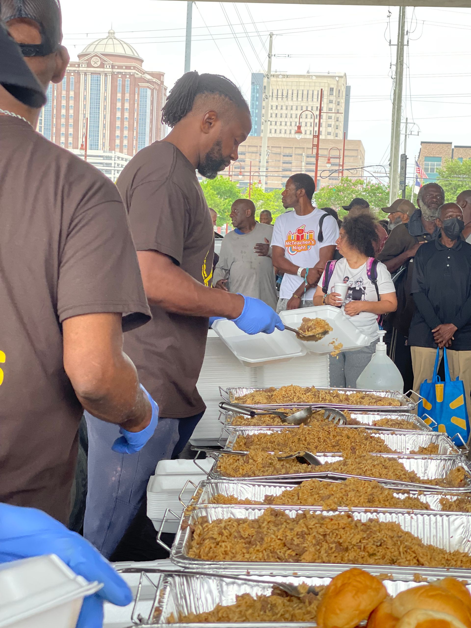 A group of people are standing around a table filled with food