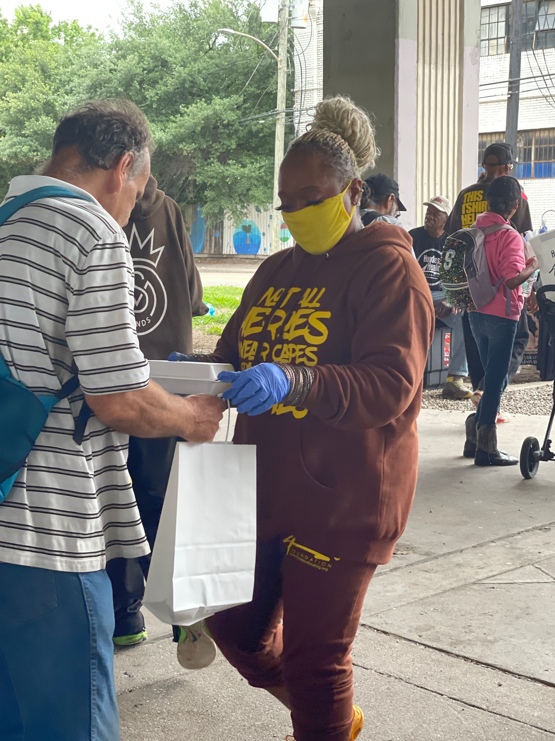 A woman wearing a mask and gloves is standing next to a man on a sidewalk.