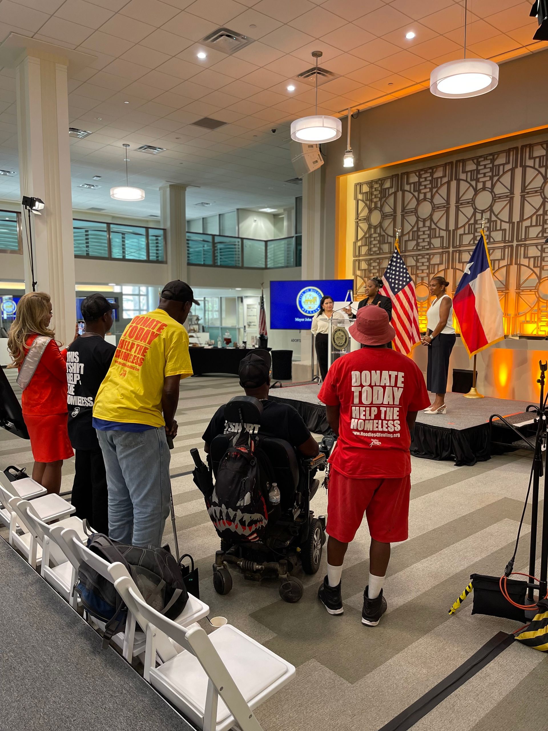 A group of people are standing in a room with a man in a wheelchair.