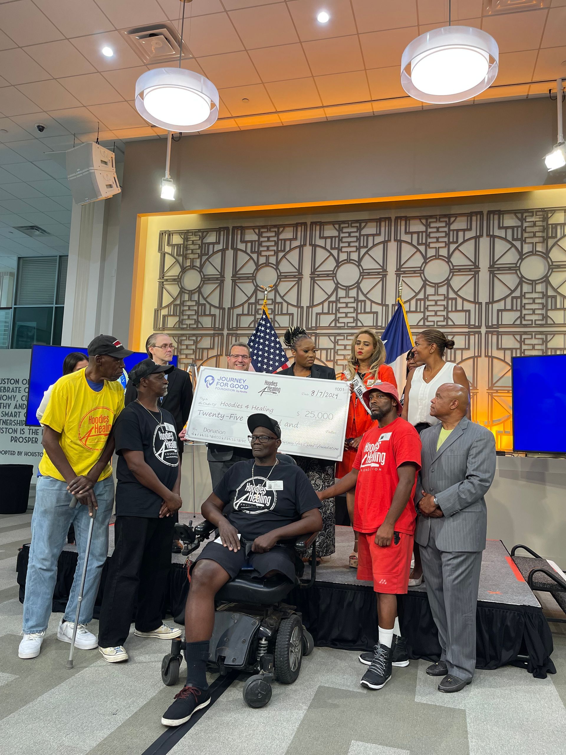 A group of people standing around a man in a wheelchair holding a large check.
