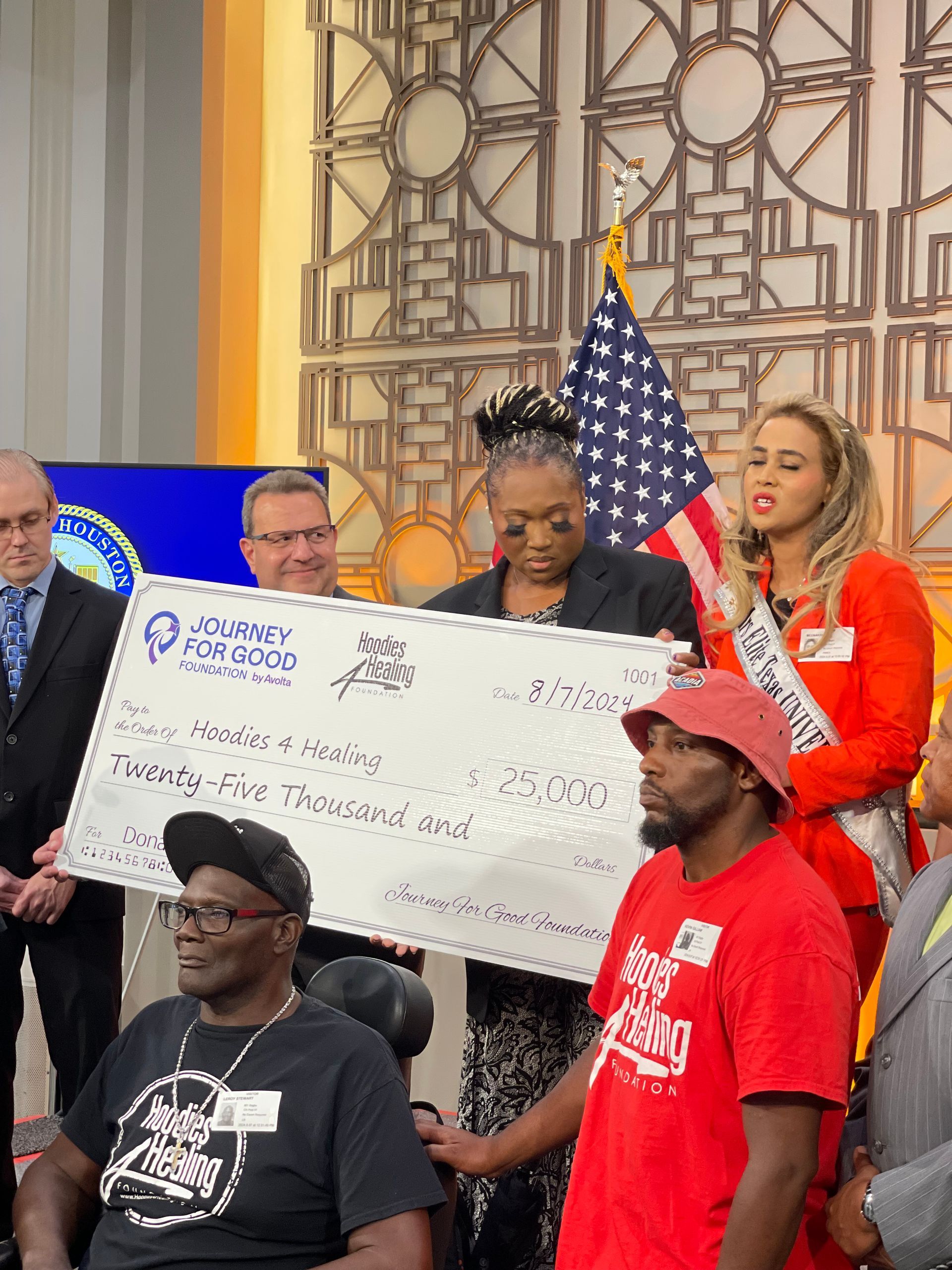 A group of people holding a large check in front of an american flag.