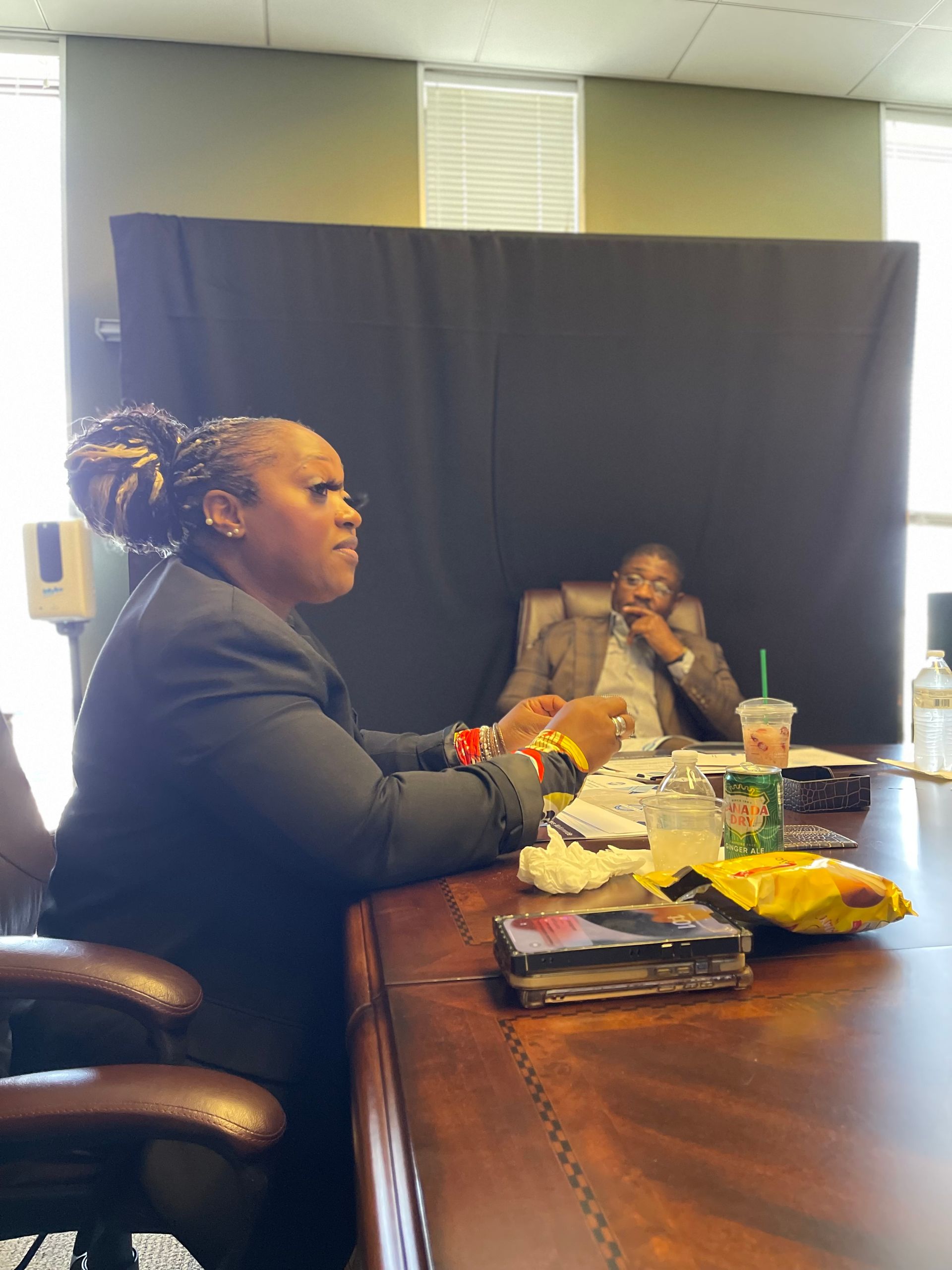 A woman is sitting at a table with a man sitting behind her.