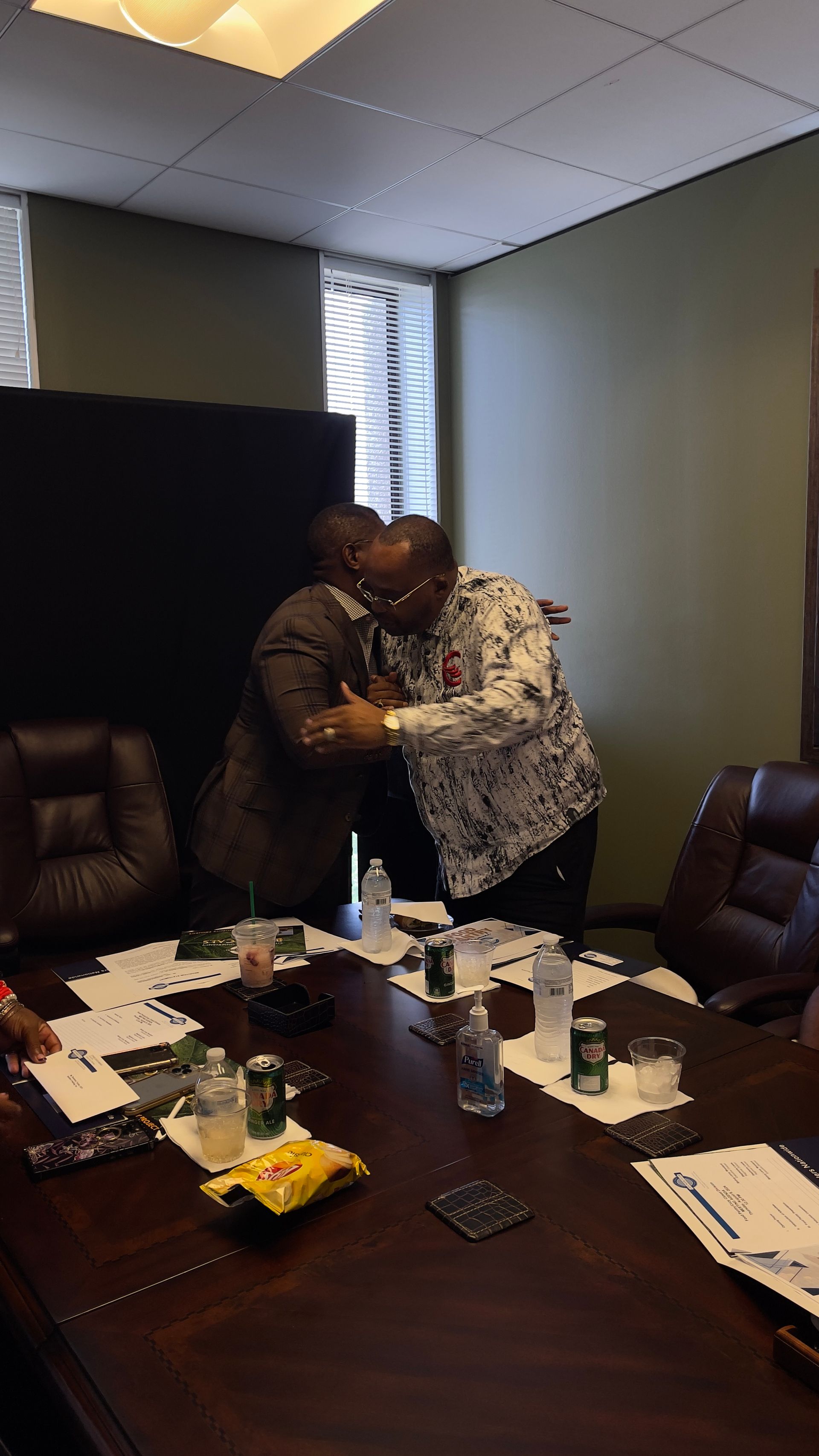 Two men are hugging each other in a conference room.