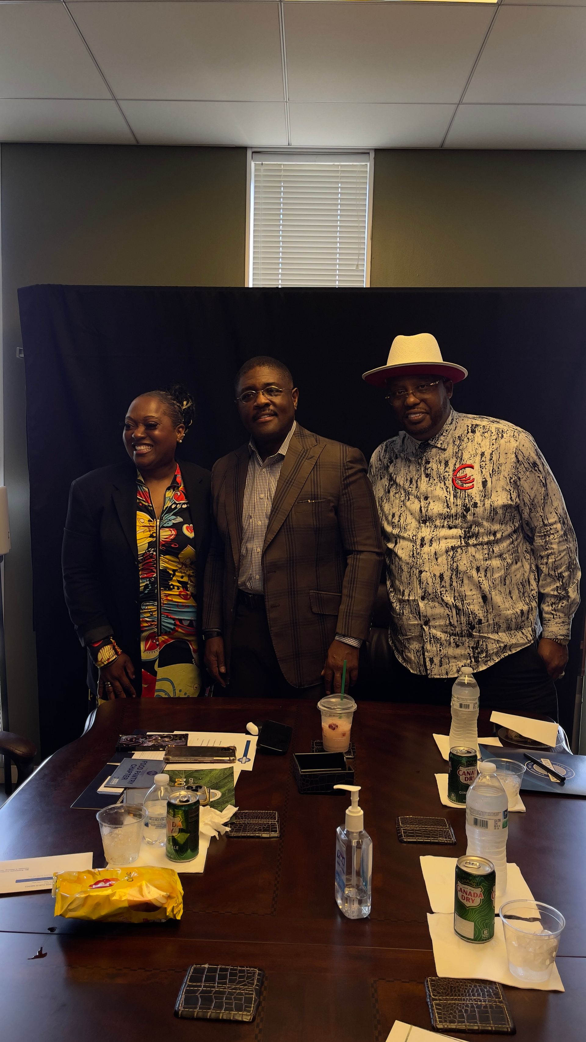 Three people are standing around a table in a conference room.