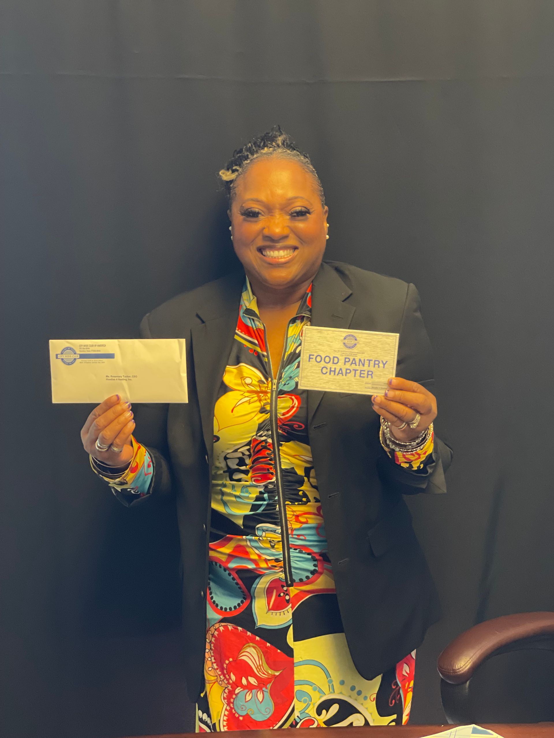 A woman in a suit is holding a check and an envelope.