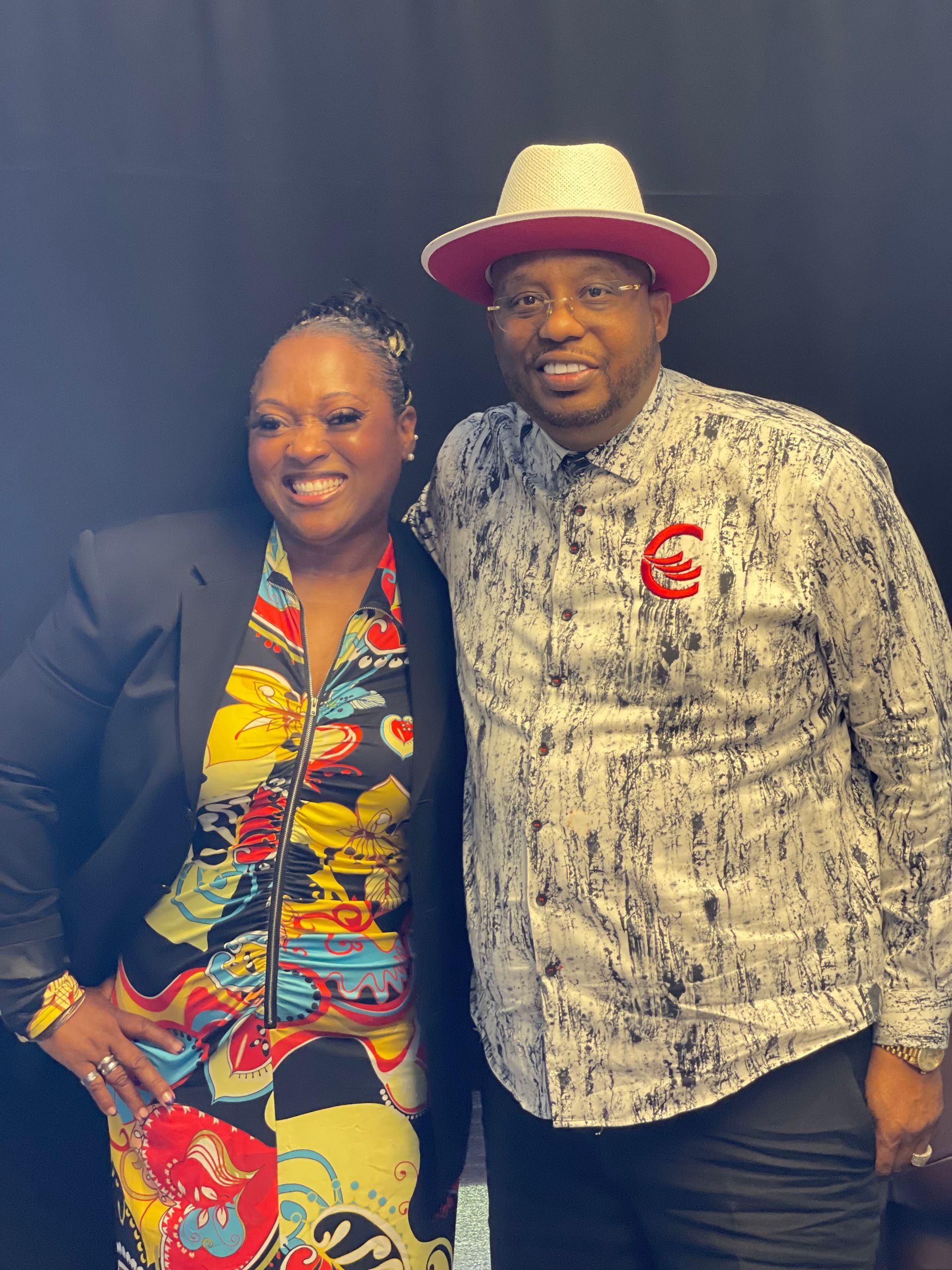 A man and a woman are posing for a picture . the man is wearing a red hat.