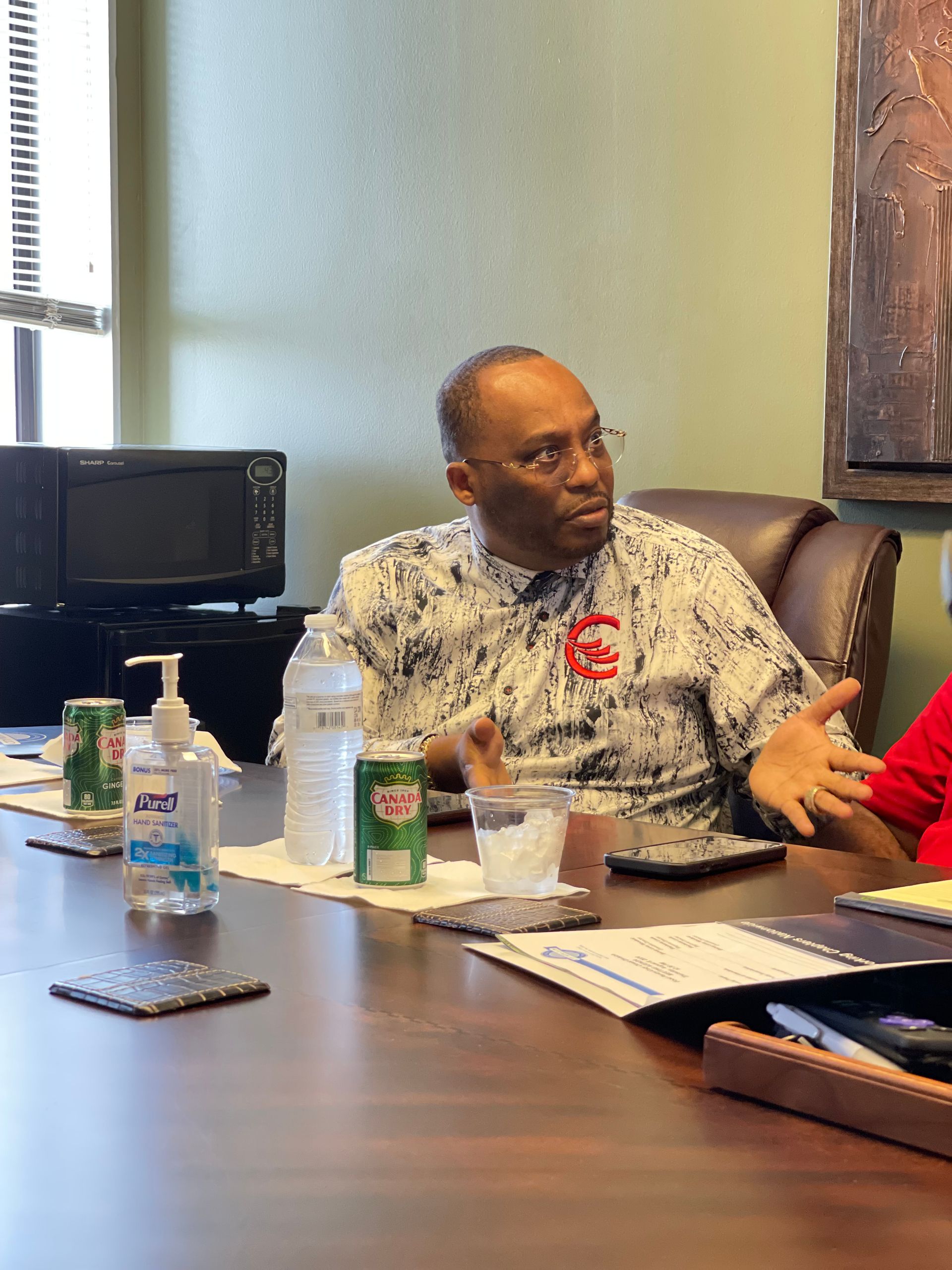 A man is sitting at a table talking to another man.