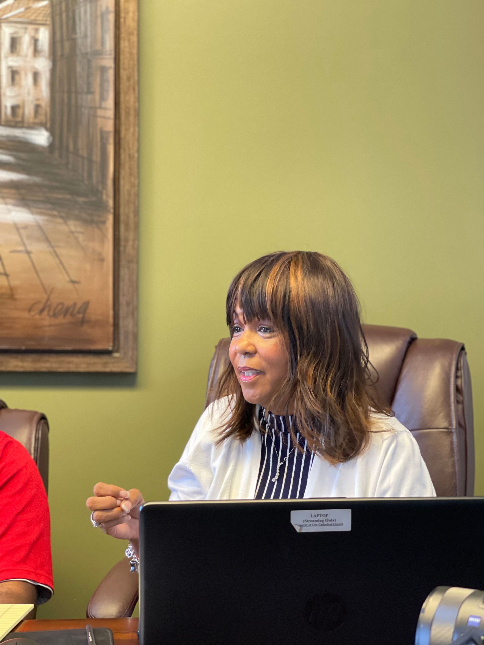 A woman is sitting at a desk in front of a laptop computer.