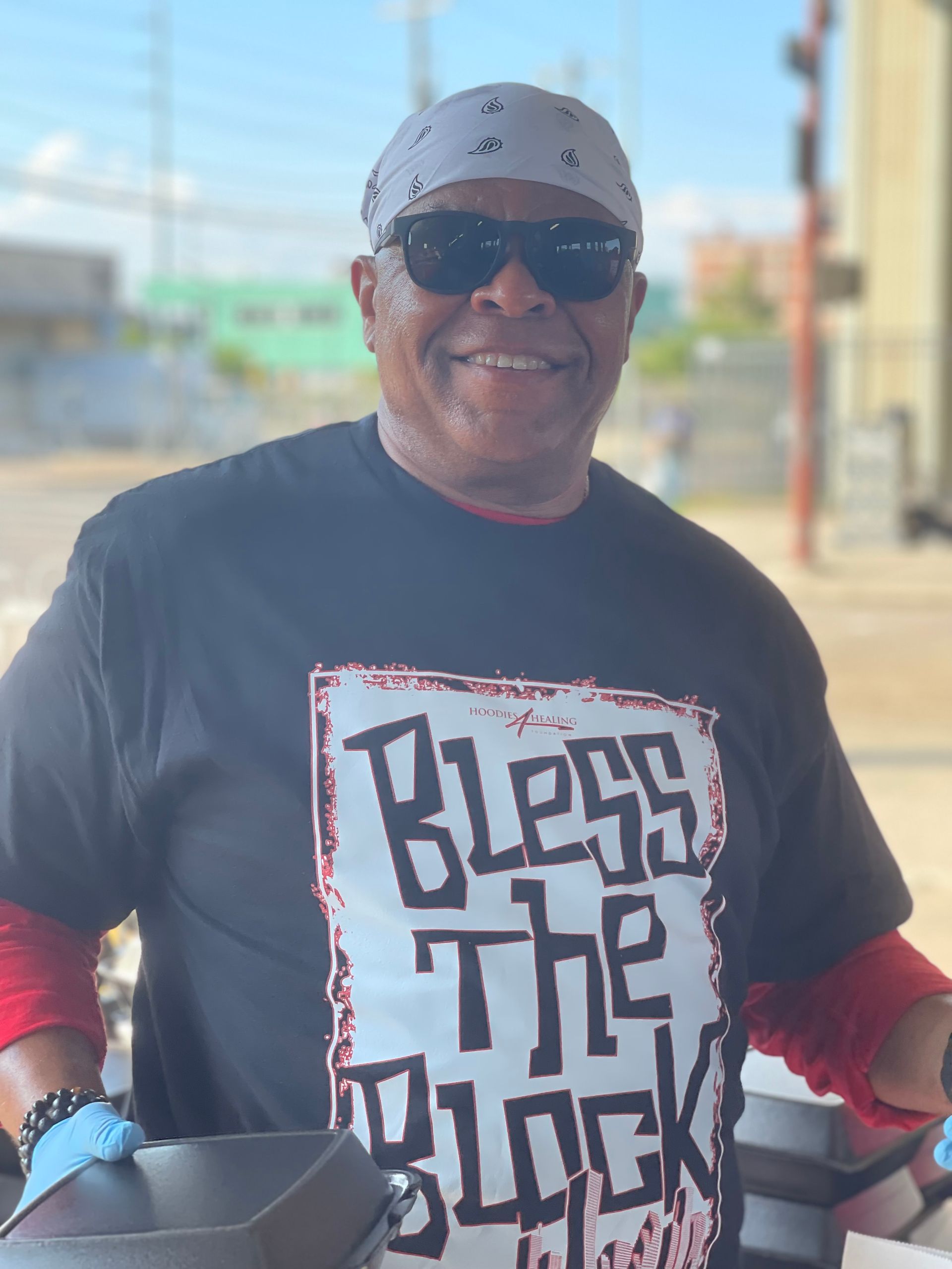 A man wearing a black shirt that says bless the block