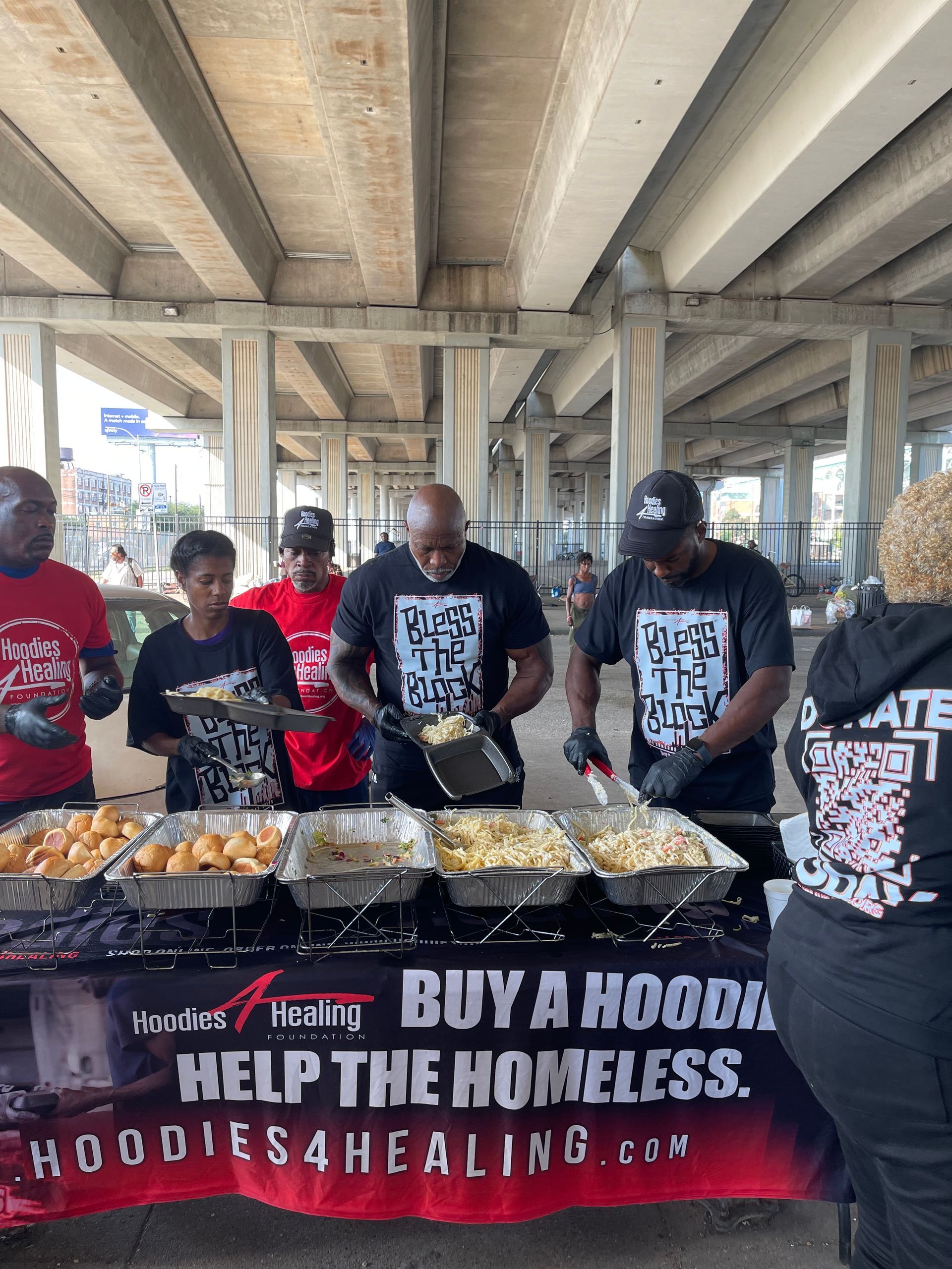 A group of people are standing around a table serving food.