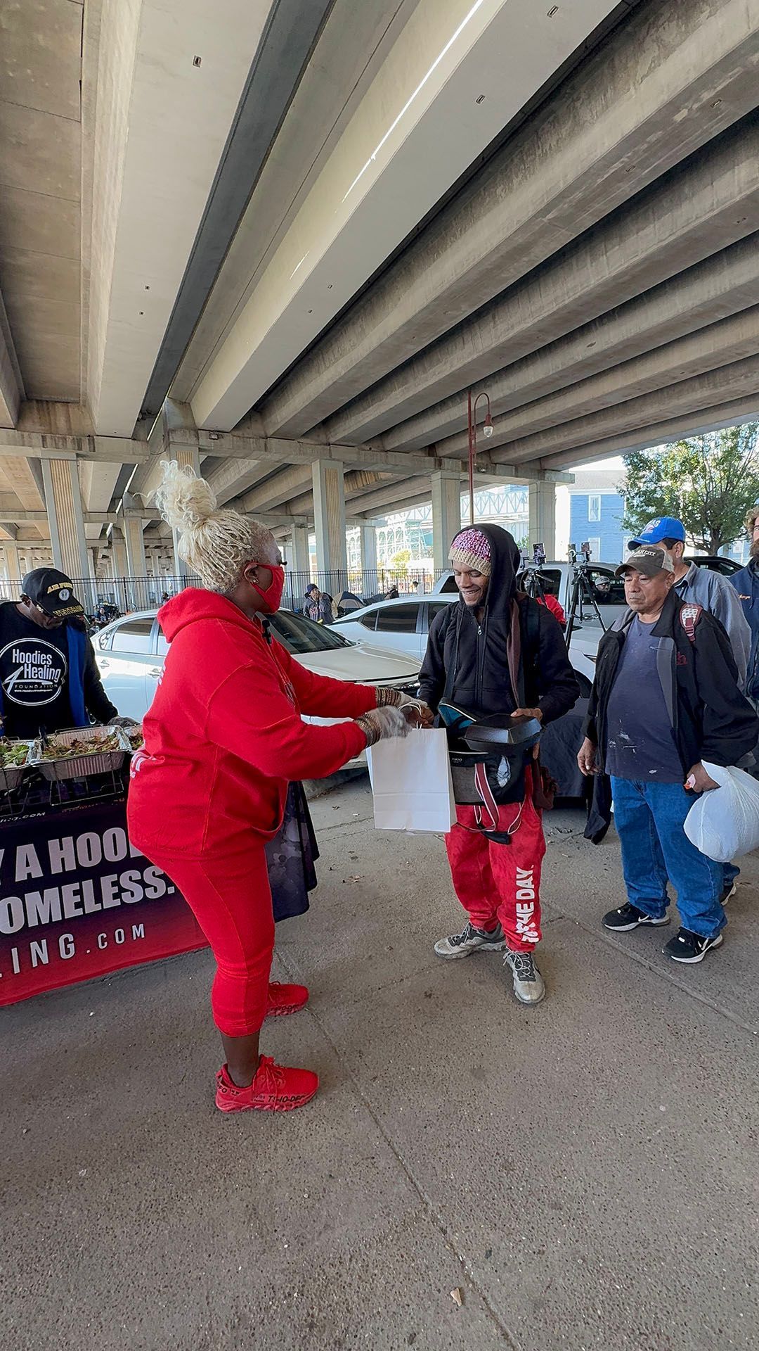 A woman in a red outfit is giving a man a piece of paper.