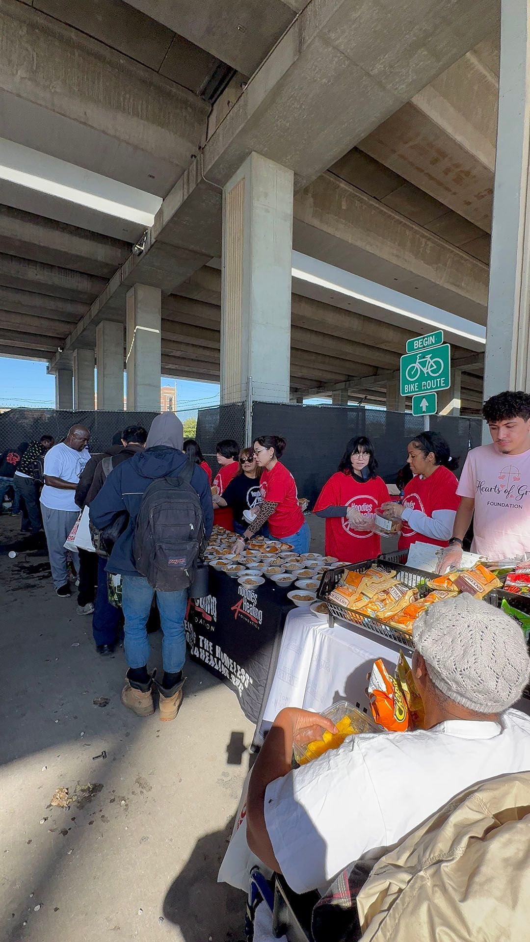 A group of people are standing around a table with food.