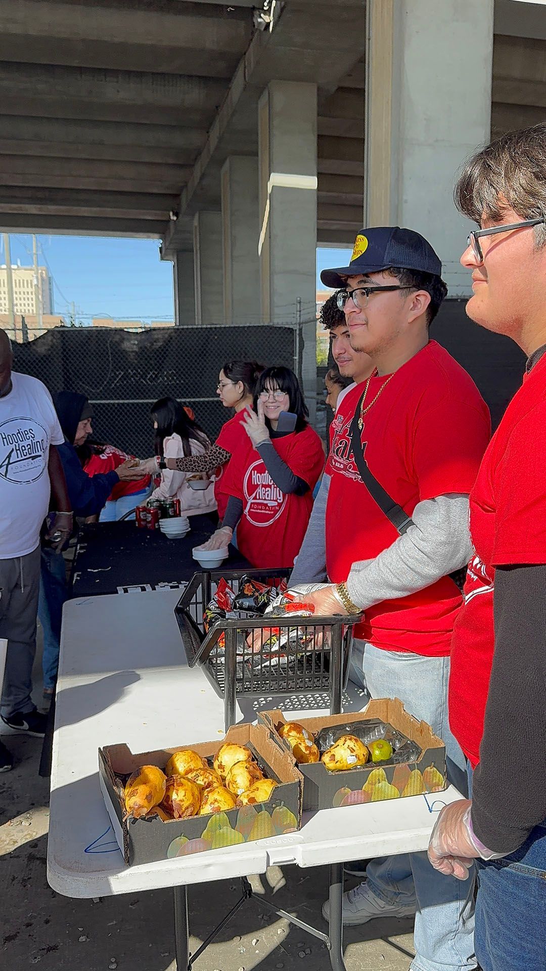 A group of people are standing around a table holding boxes of food.