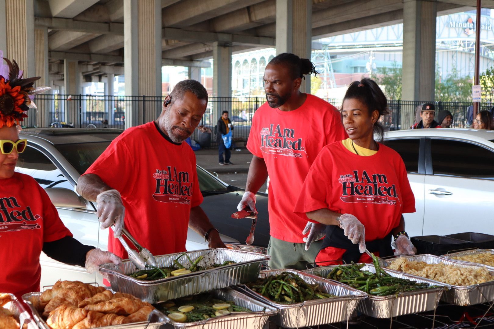 A group of people are standing around a table serving food.