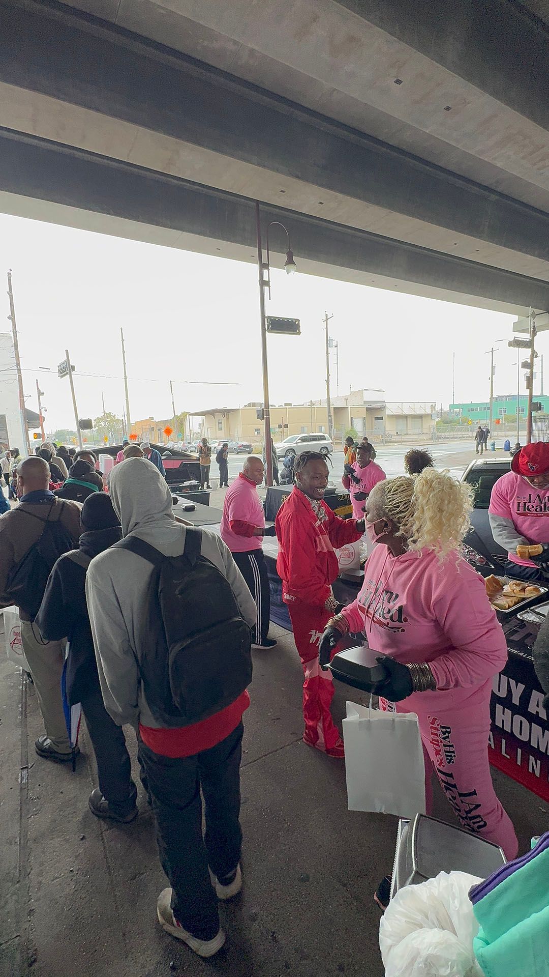 A group of people are standing around a table under a bridge.