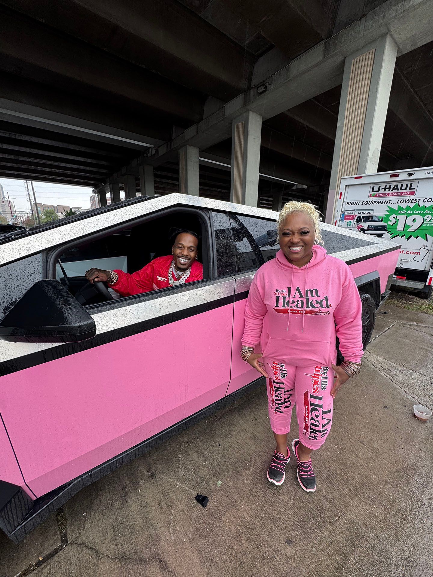 A man and a woman are standing next to a pink car.
