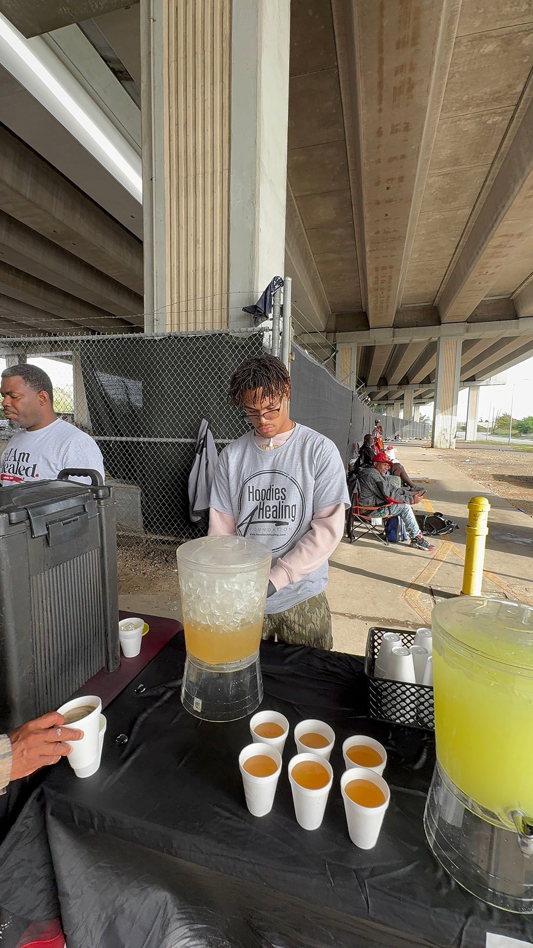 A man is pouring a drink from a pitcher into cups.