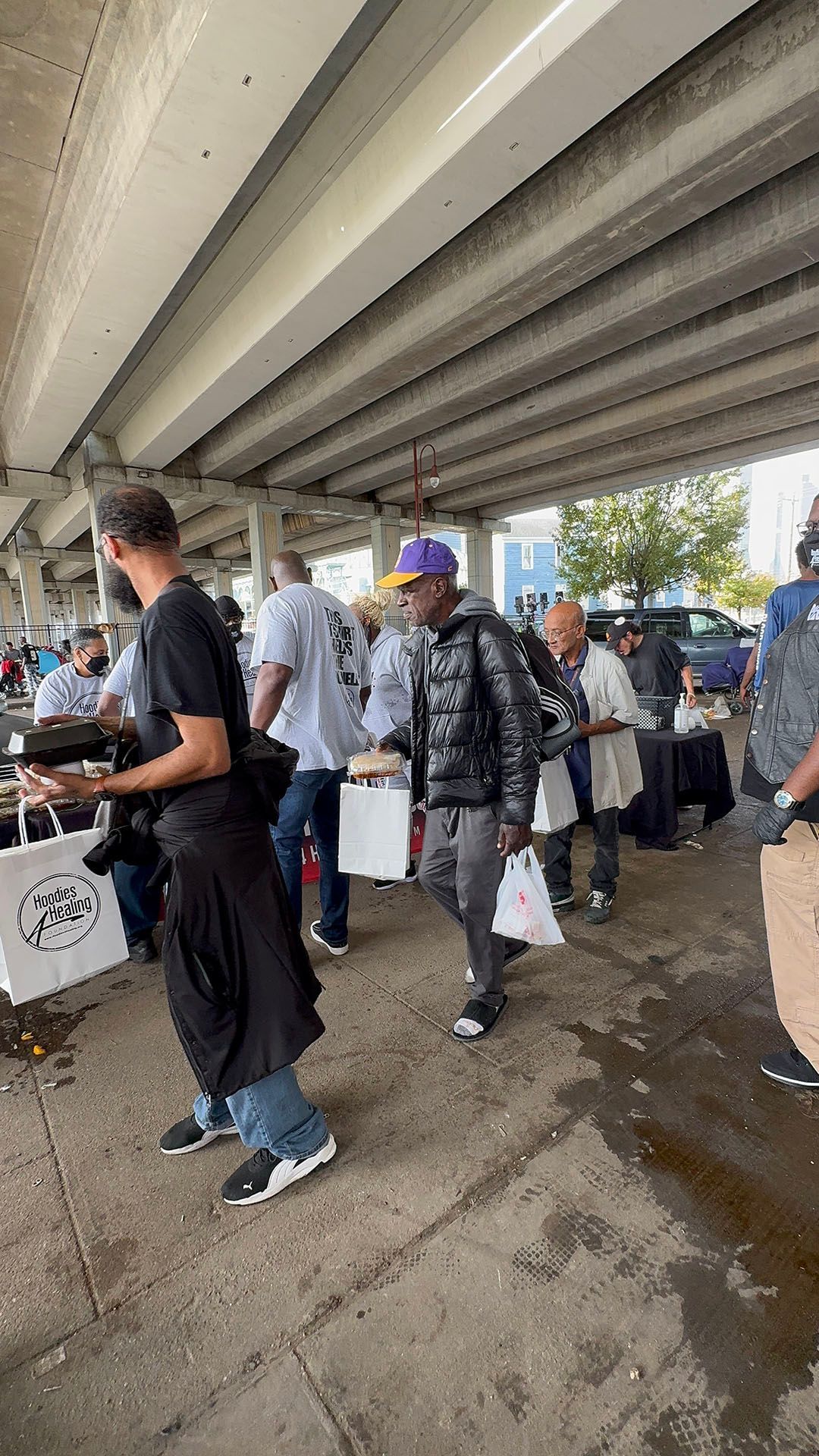 A group of people are walking under a bridge.