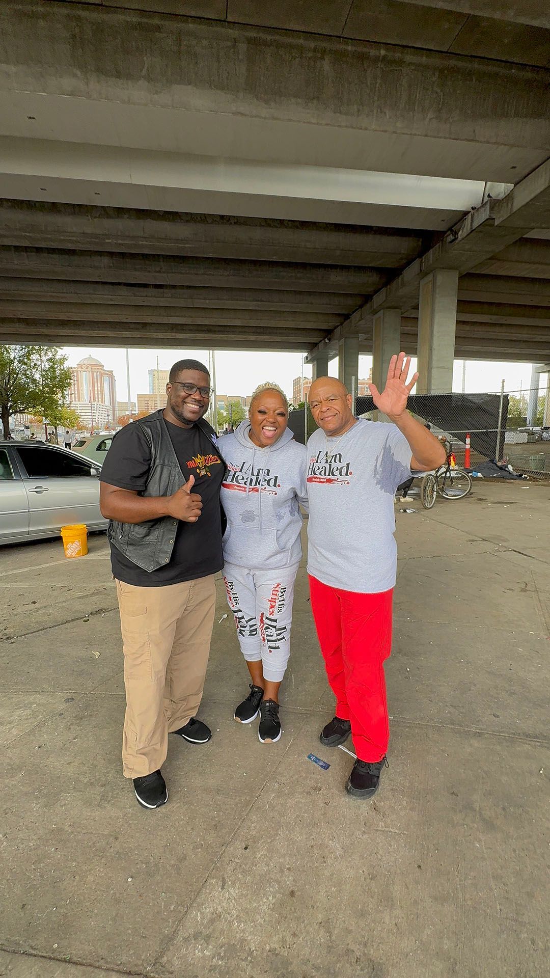 Three people are posing for a picture under a bridge.