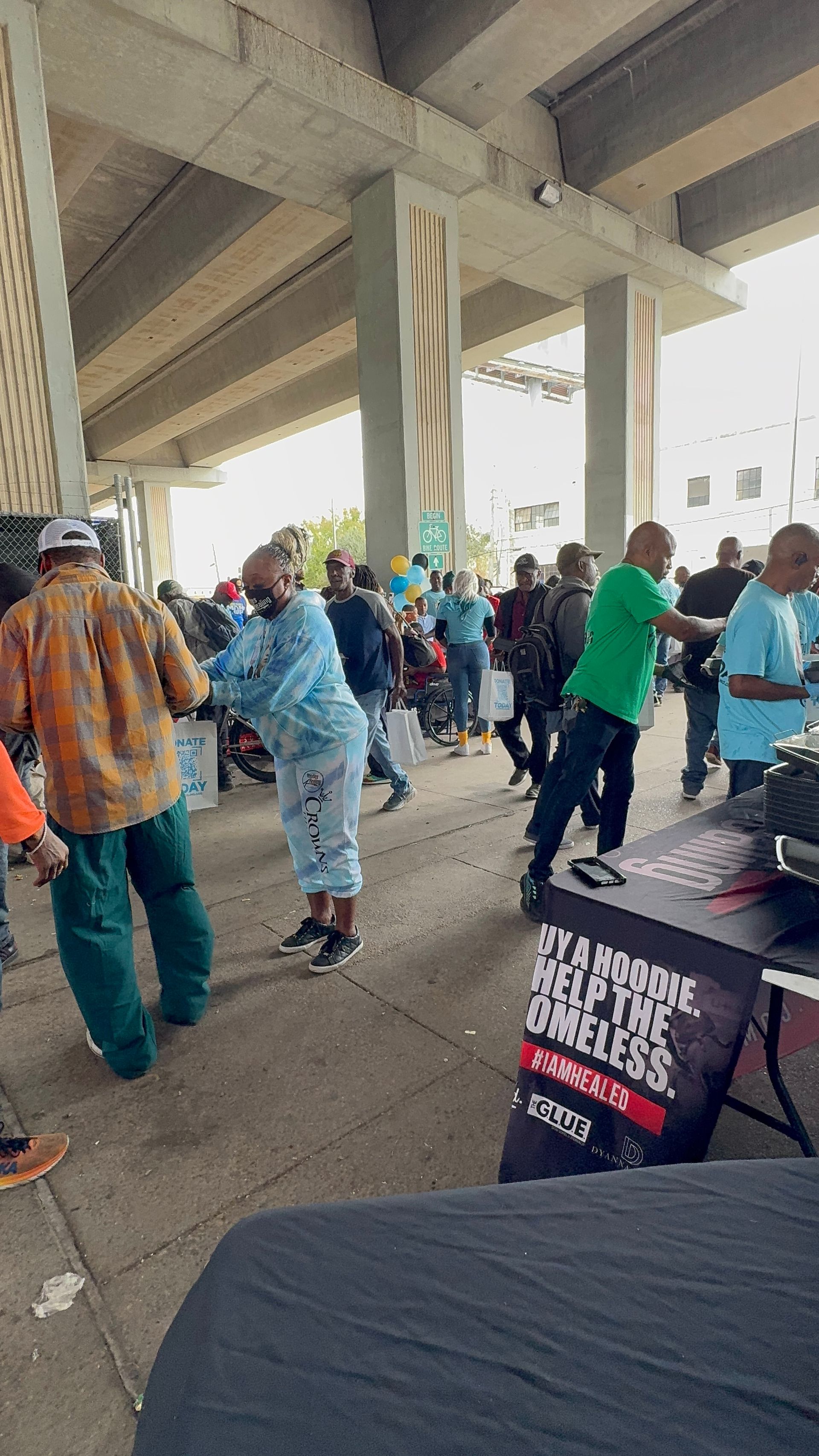 A group of people are dancing under a bridge.