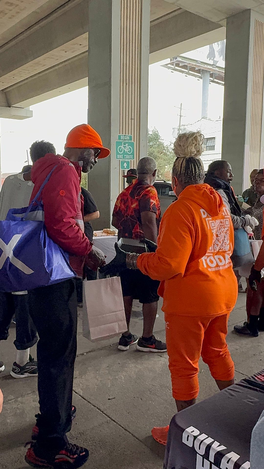 A group of people are standing in a line under a bridge.