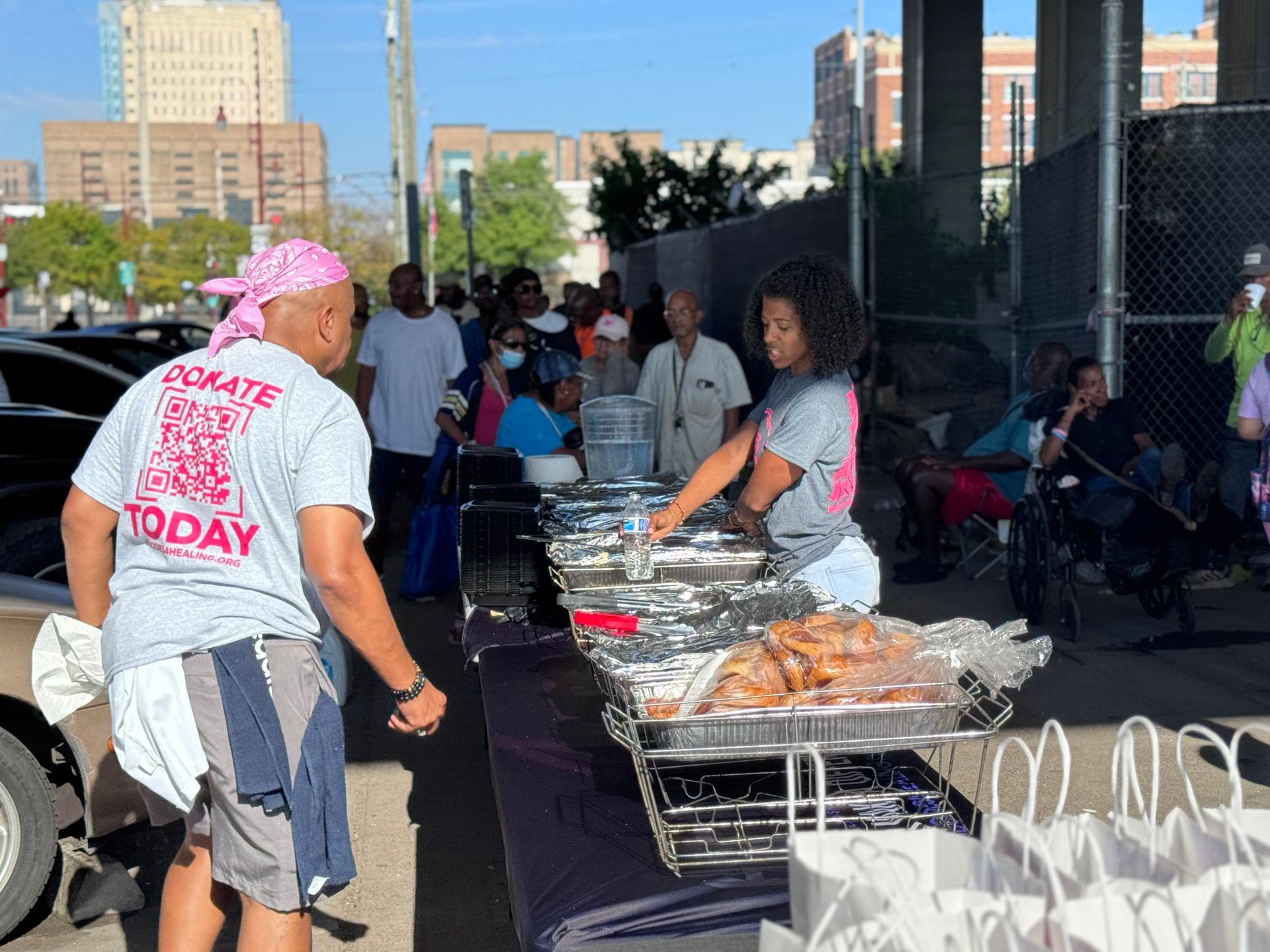 A man wearing a shirt that says donate today is standing next to a woman serving food.