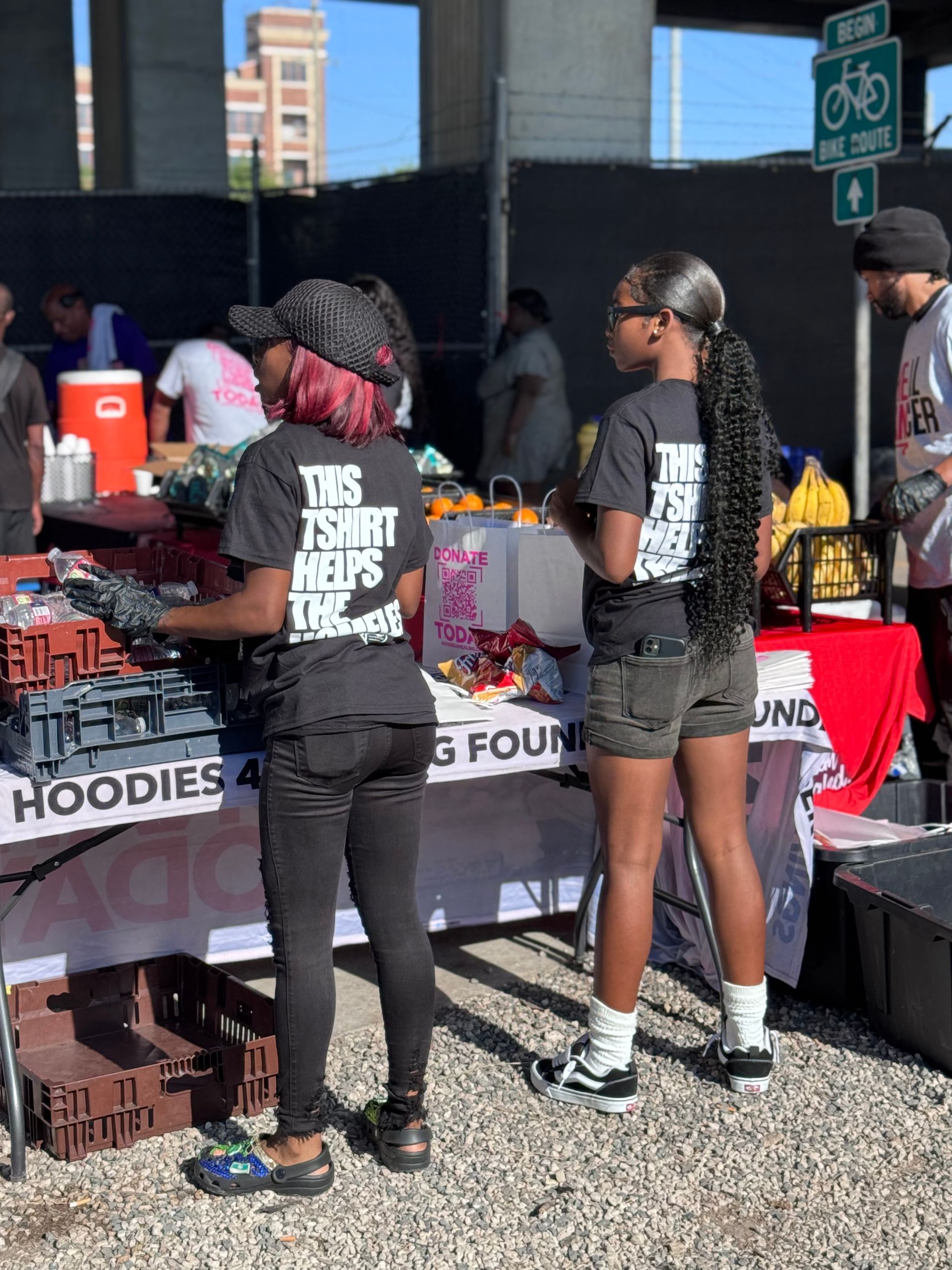 Two women standing in front of a table that says hoodies