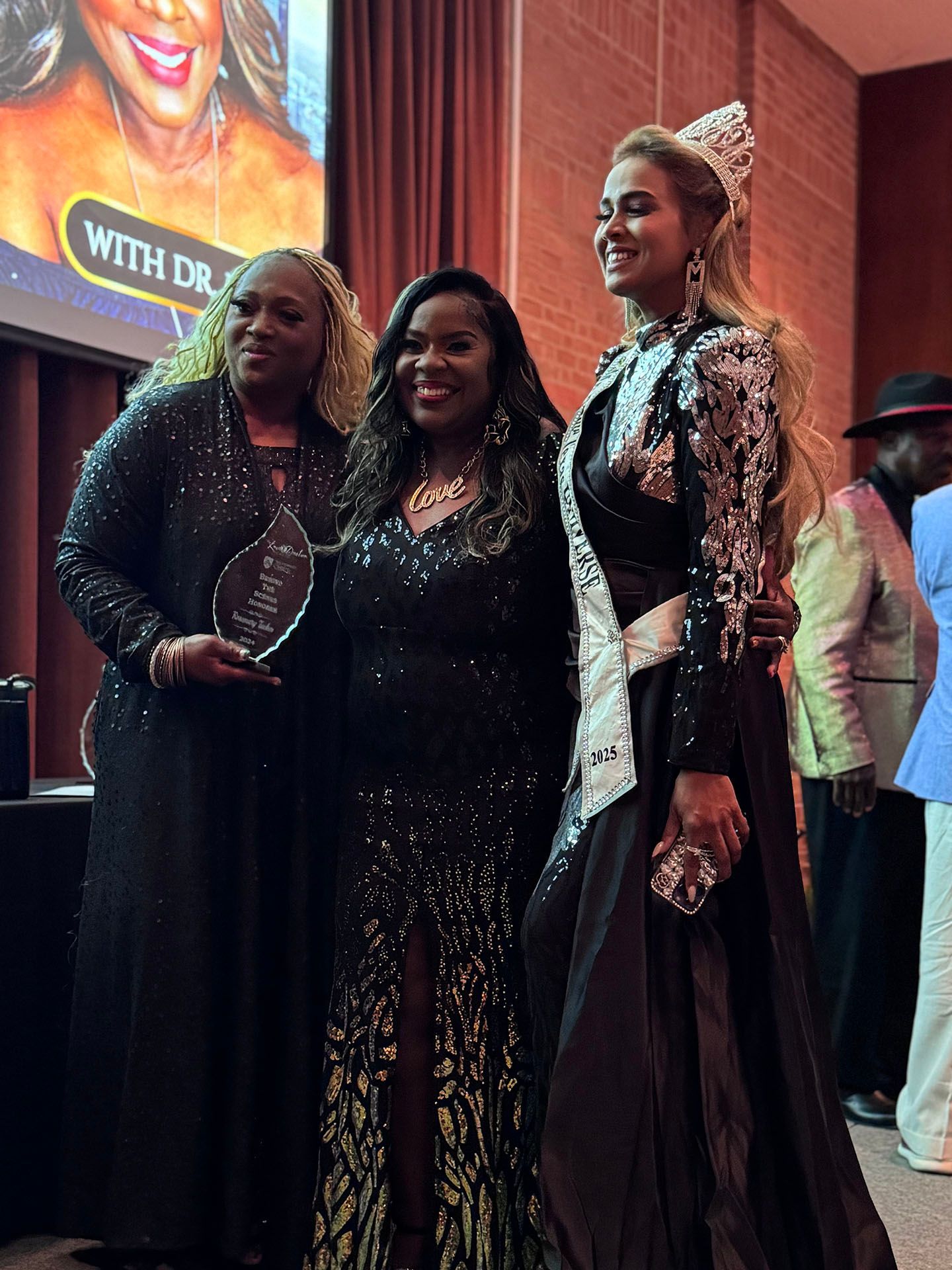 Three women are posing for a picture in front of a screen that says with dr.