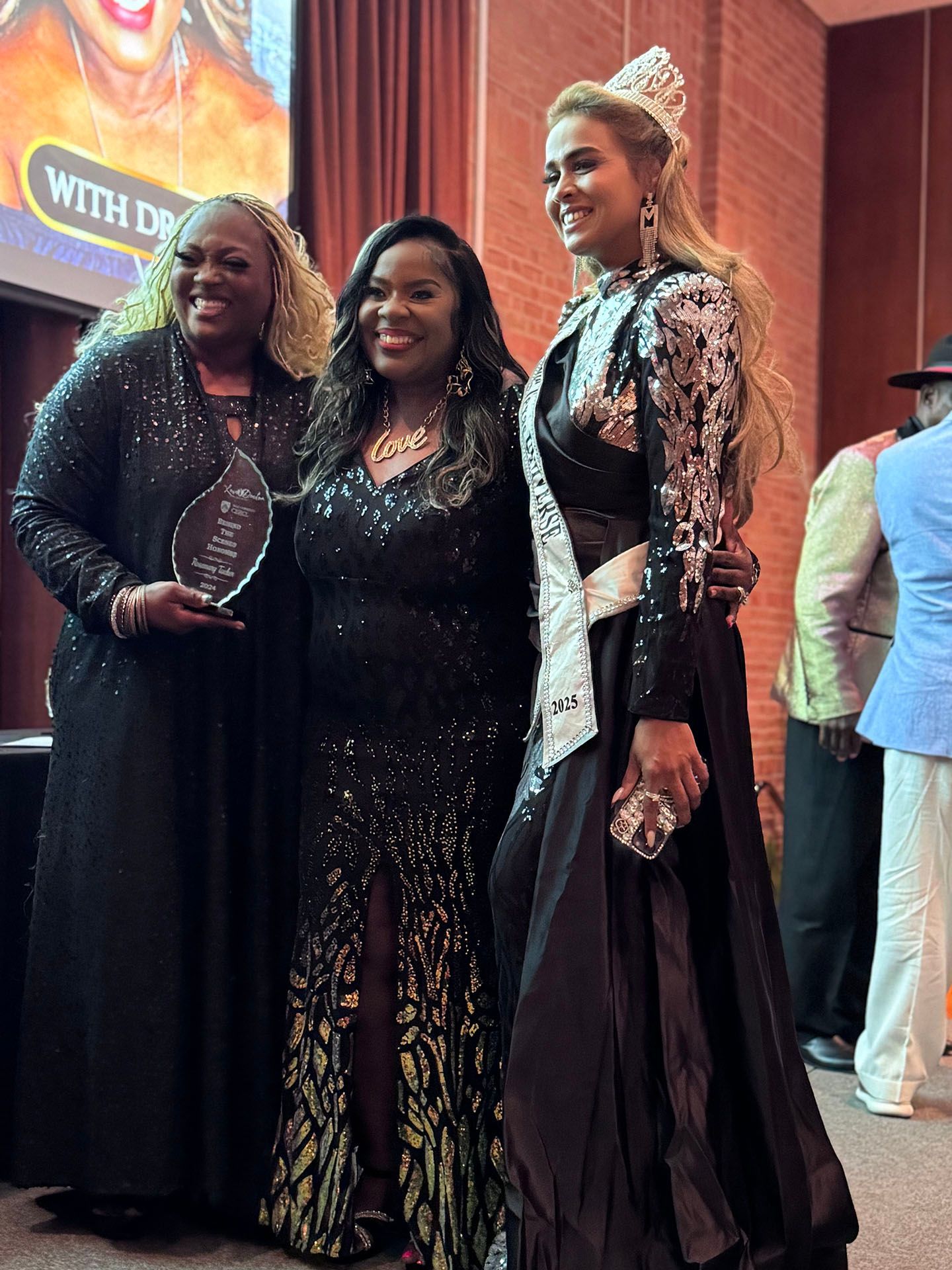 Three women in black dresses are posing for a picture