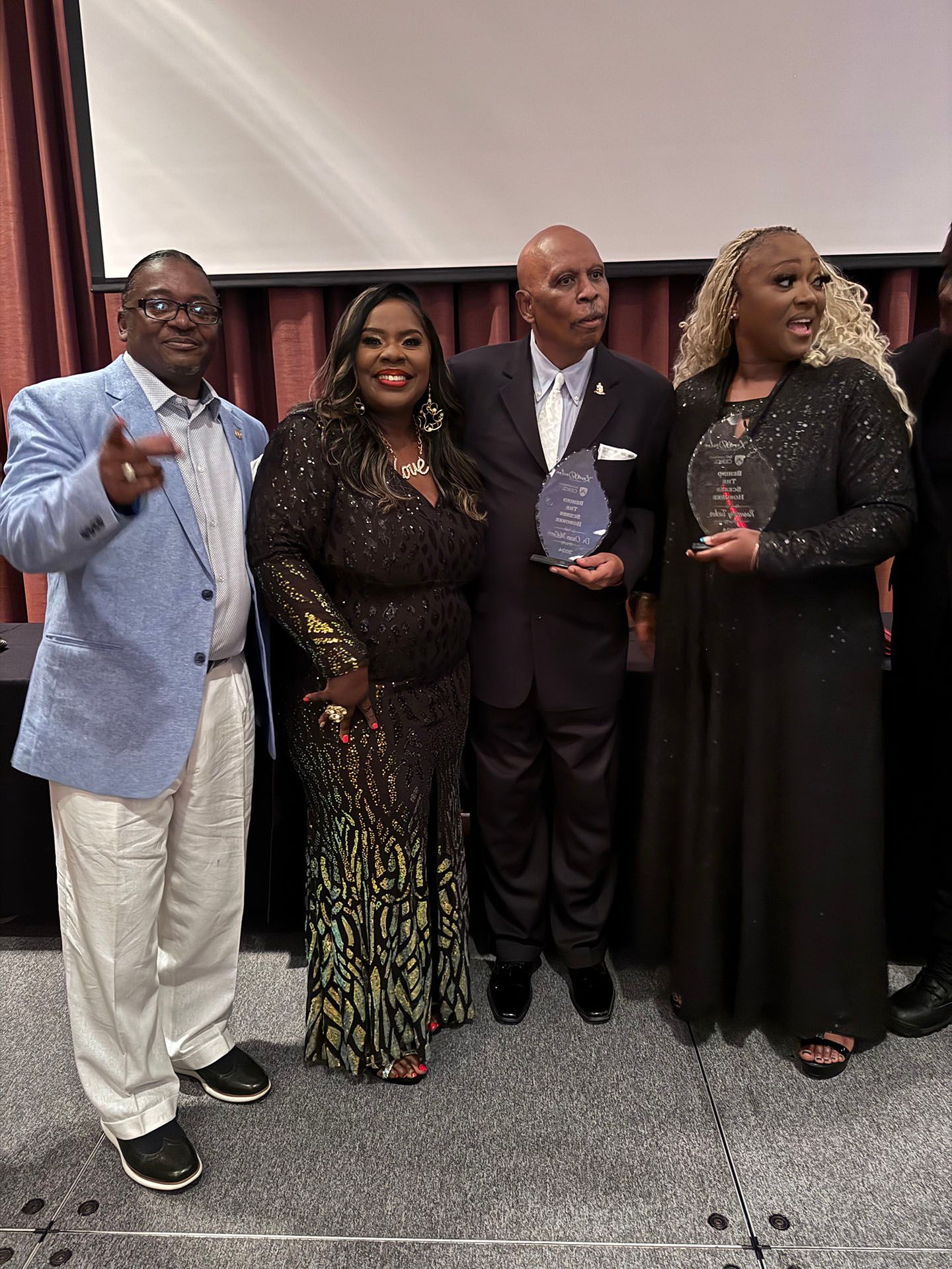 A group of people standing next to each other on a stage holding awards.