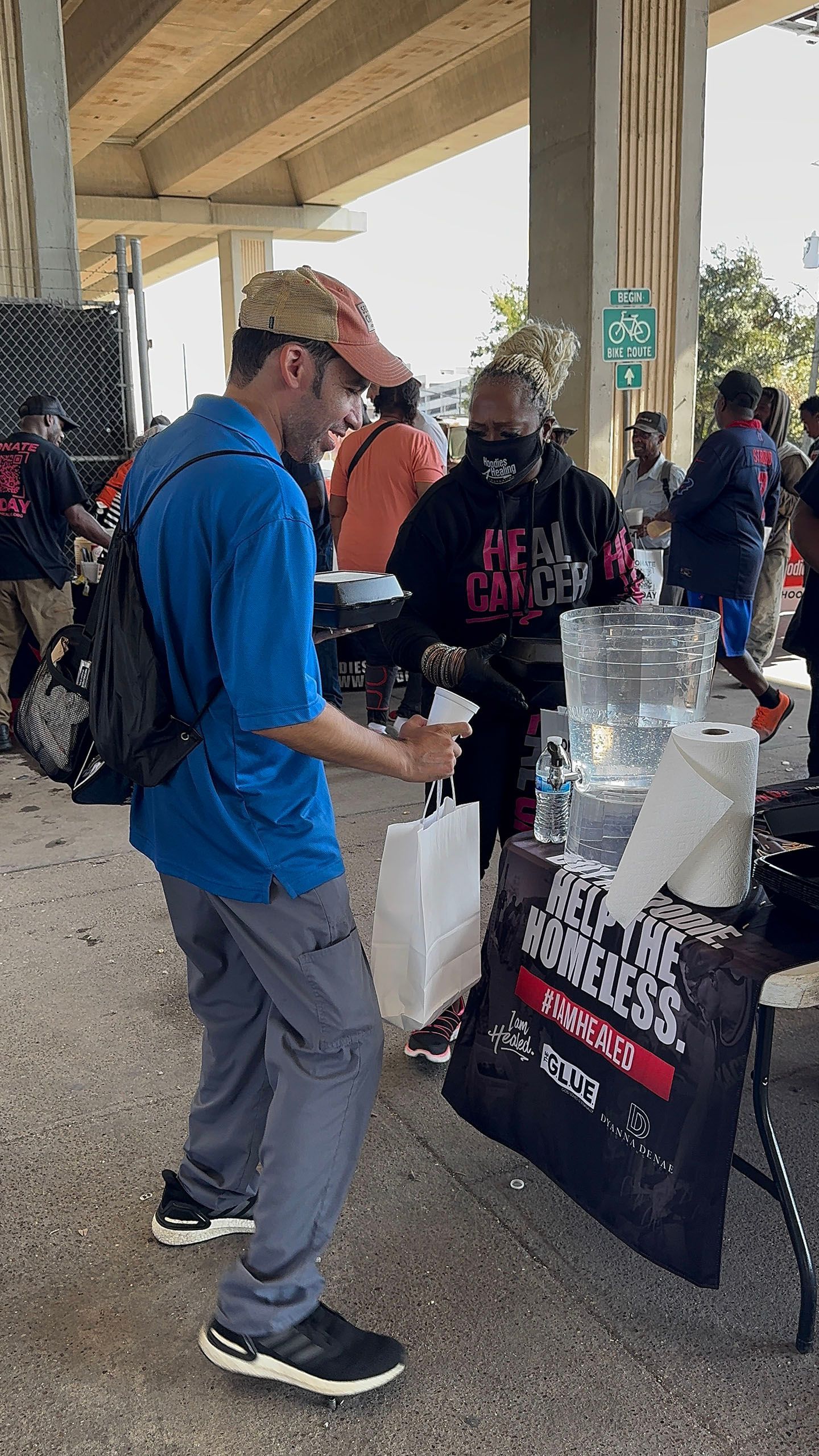 A man in a blue shirt is standing in front of a table.