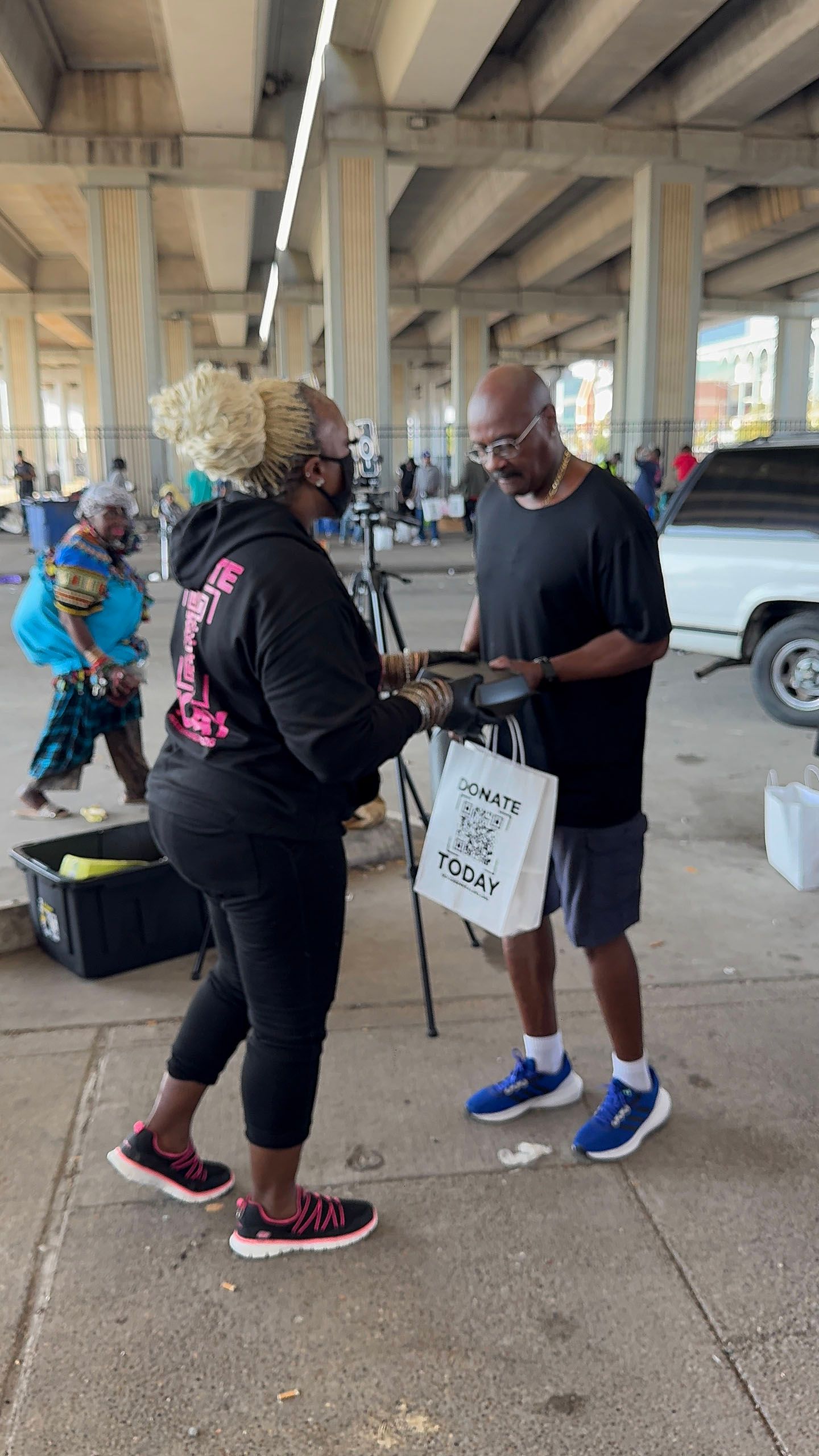 A man and a woman are shaking hands under a bridge.