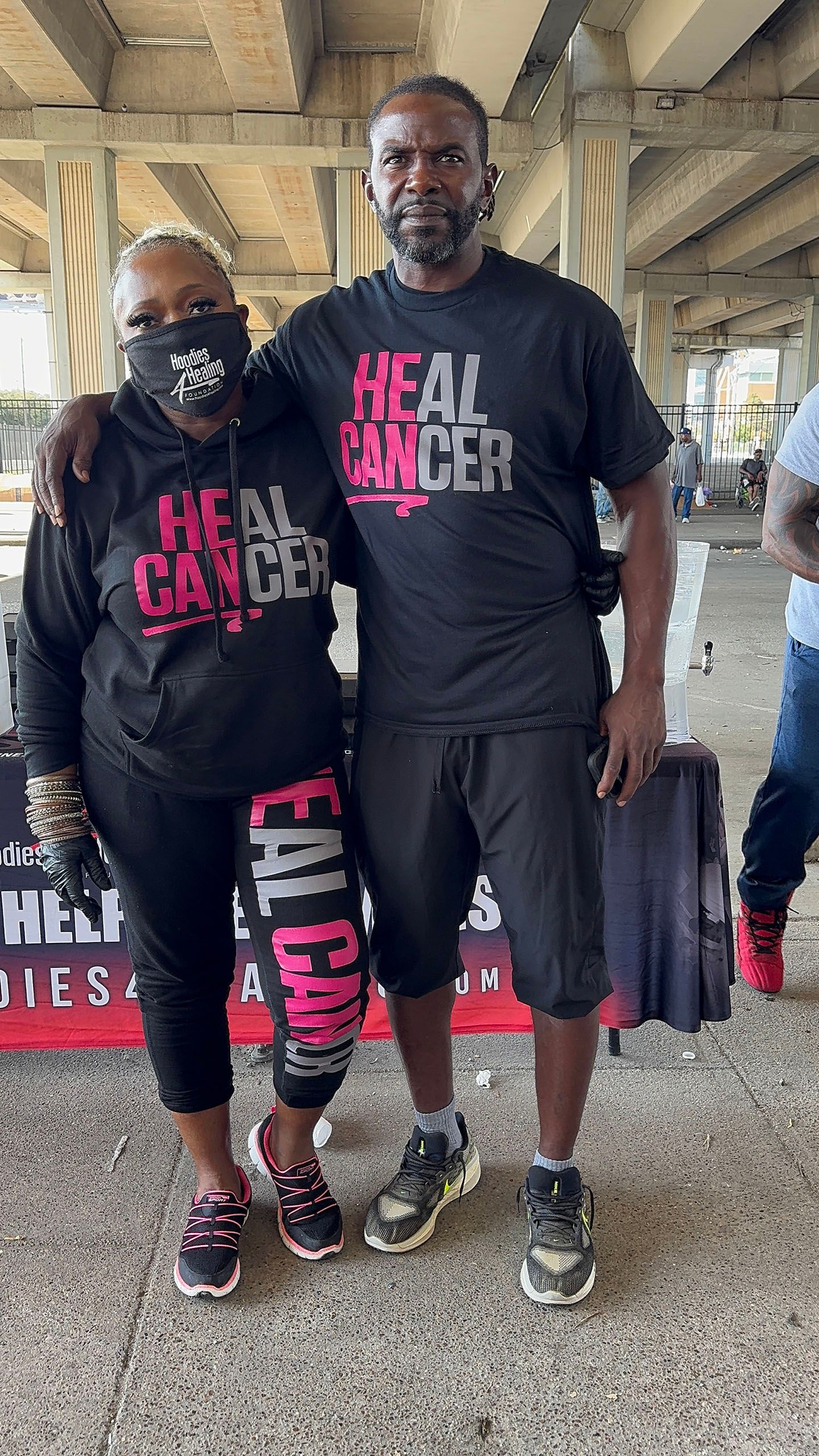 A man and a woman are standing next to each other under a bridge.