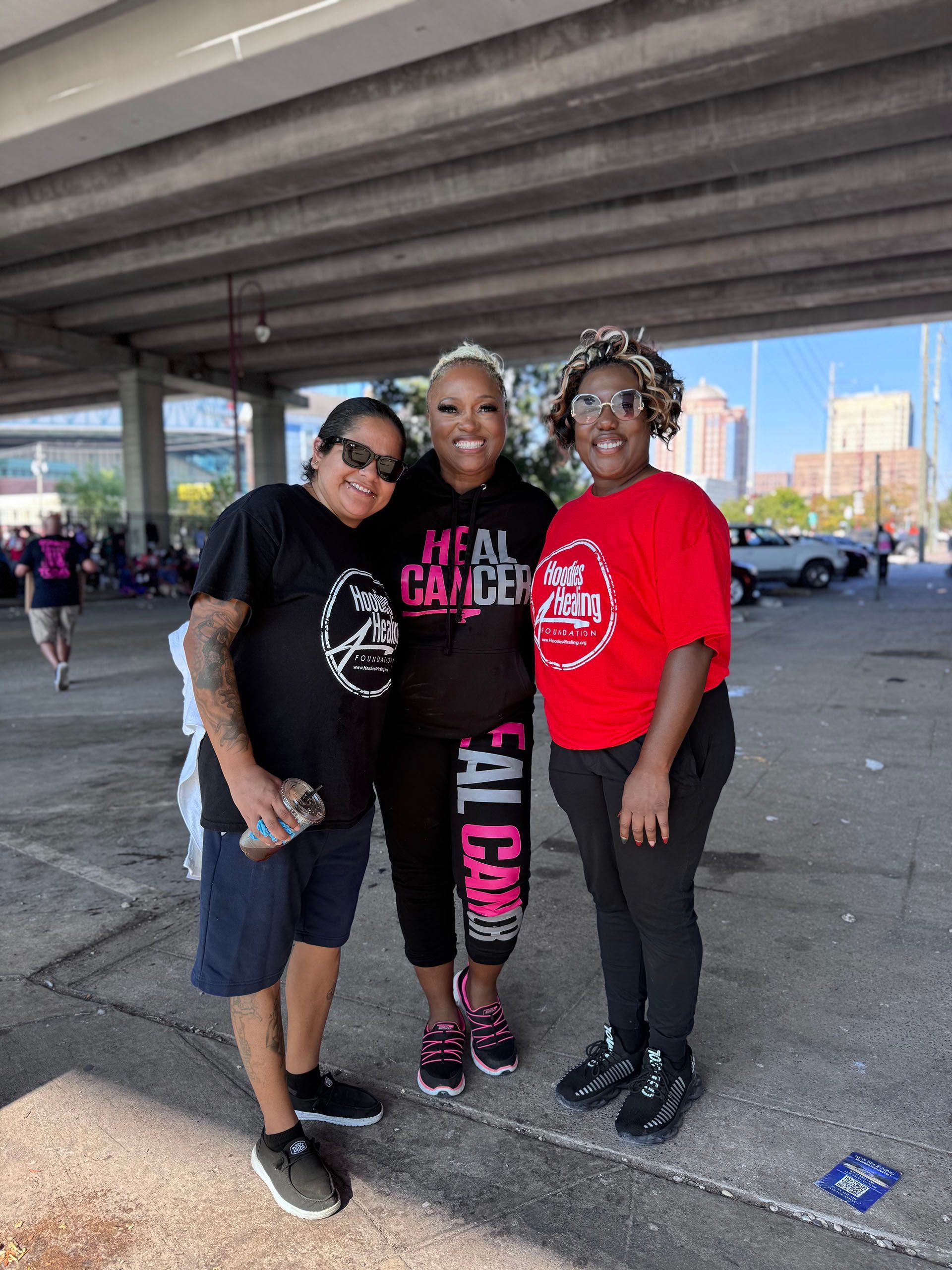 Three people are posing for a picture in a parking lot.