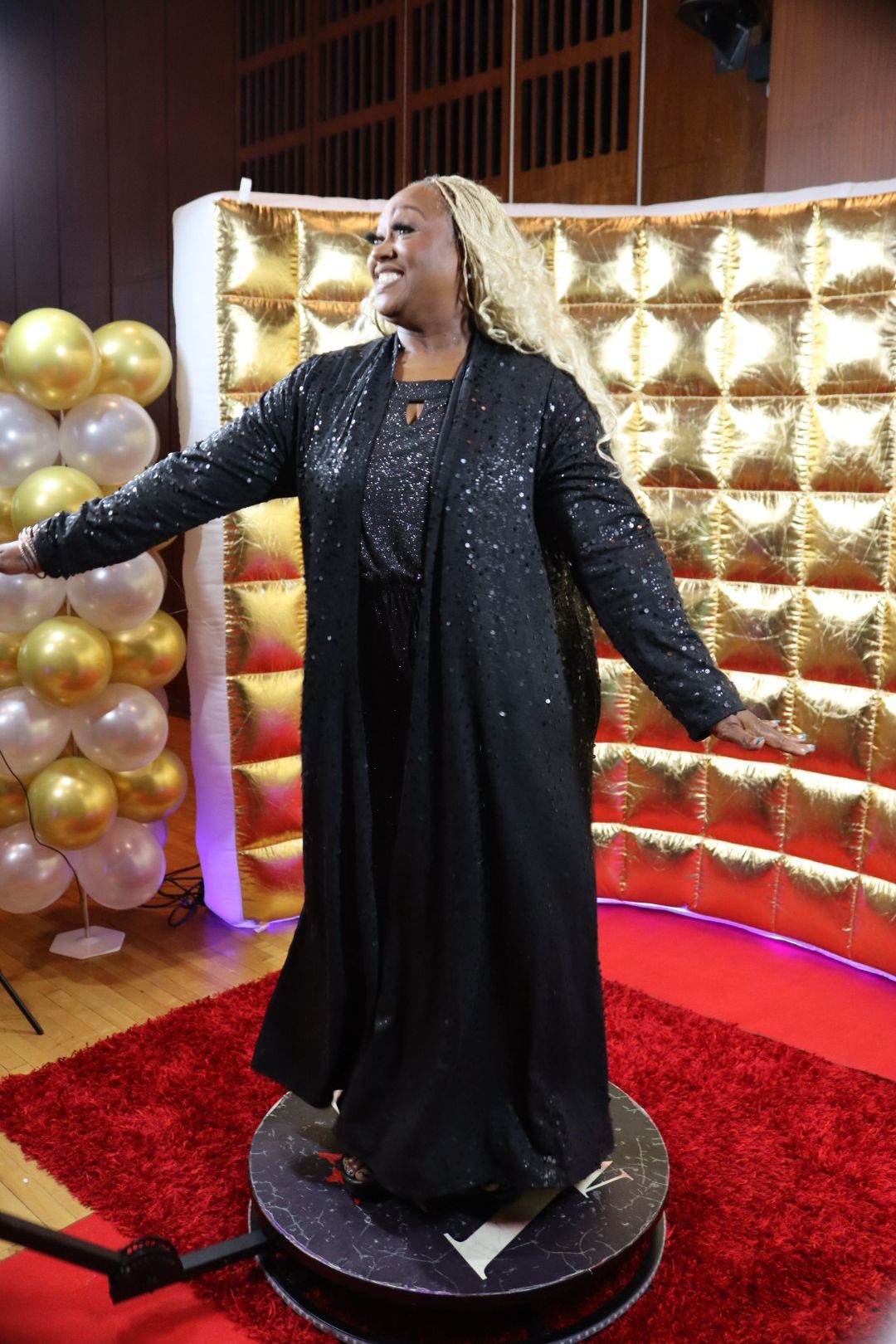 A woman in a black dress is standing on a red carpet.