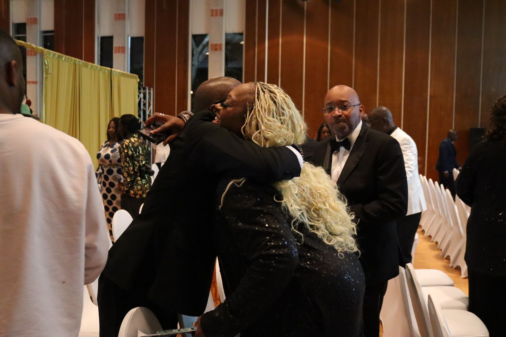 A man in a tuxedo is hugging a woman in a black dress