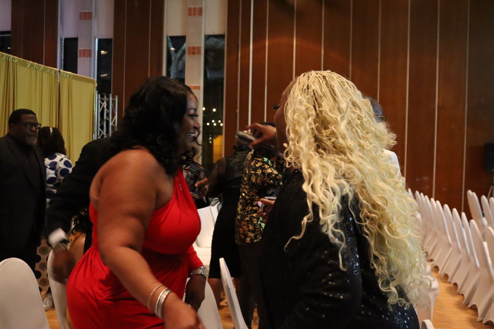 A woman in a red dress is standing next to another woman with blonde hair.
