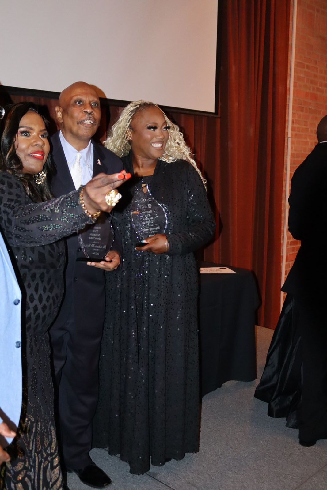 A group of people posing for a picture in front of a screen