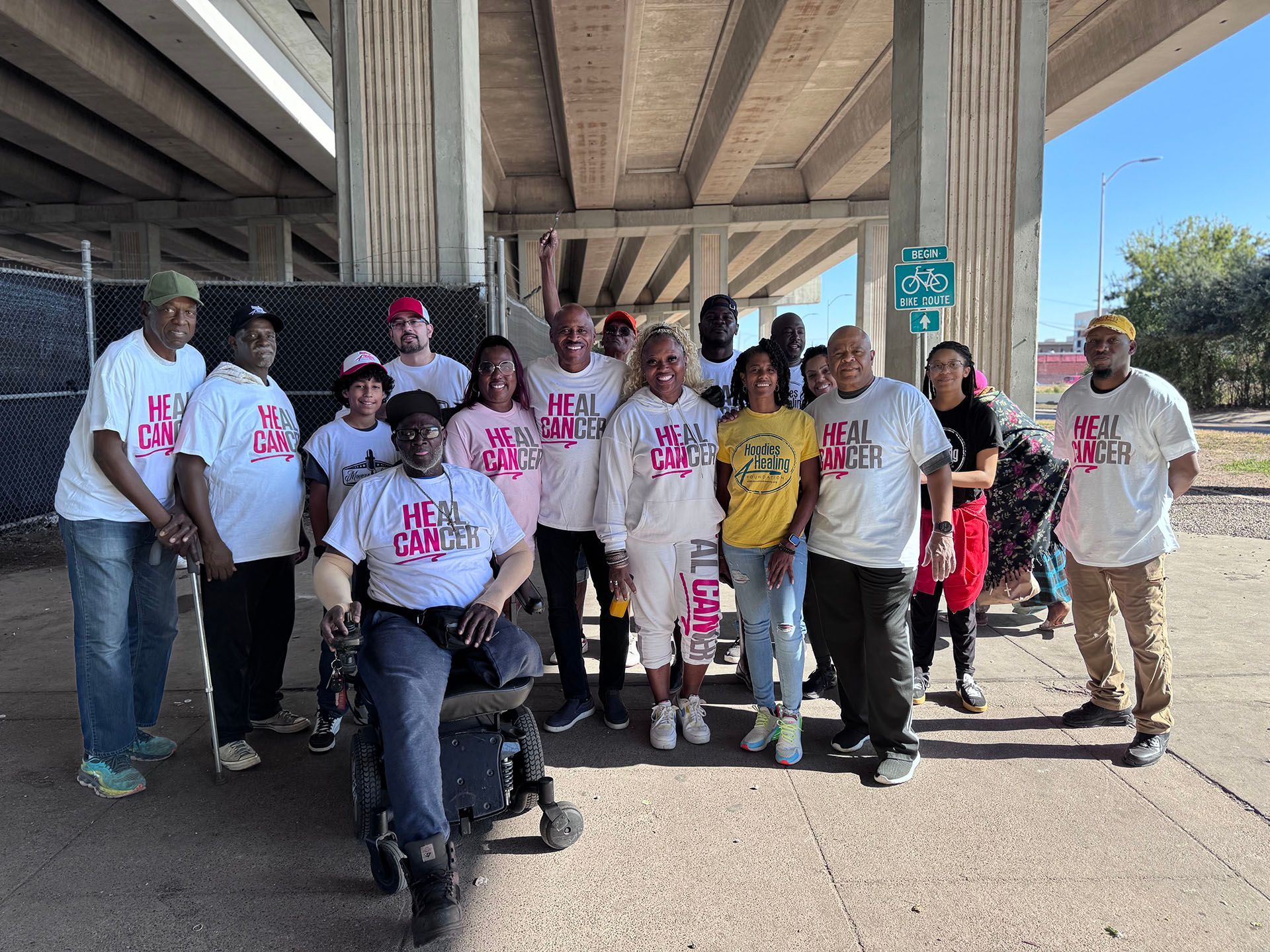 A group of people are posing for a picture under a bridge.